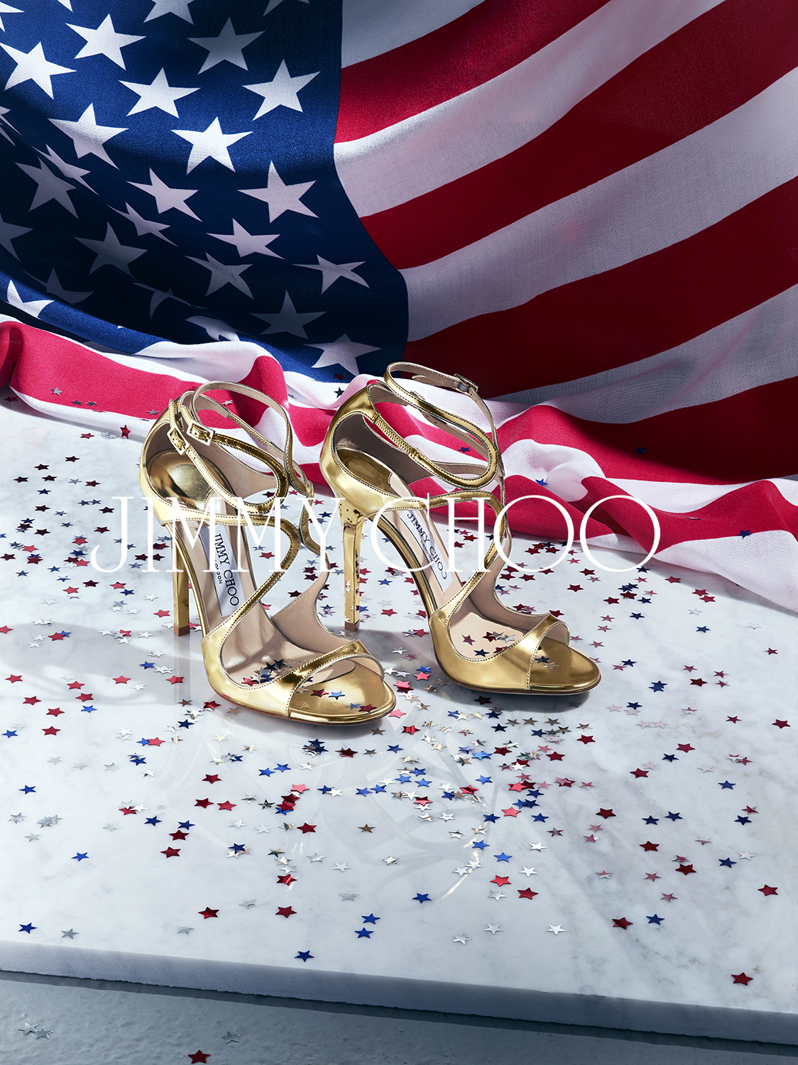 A pair of golden Jimmy Choo stilettos in front of the American flag
