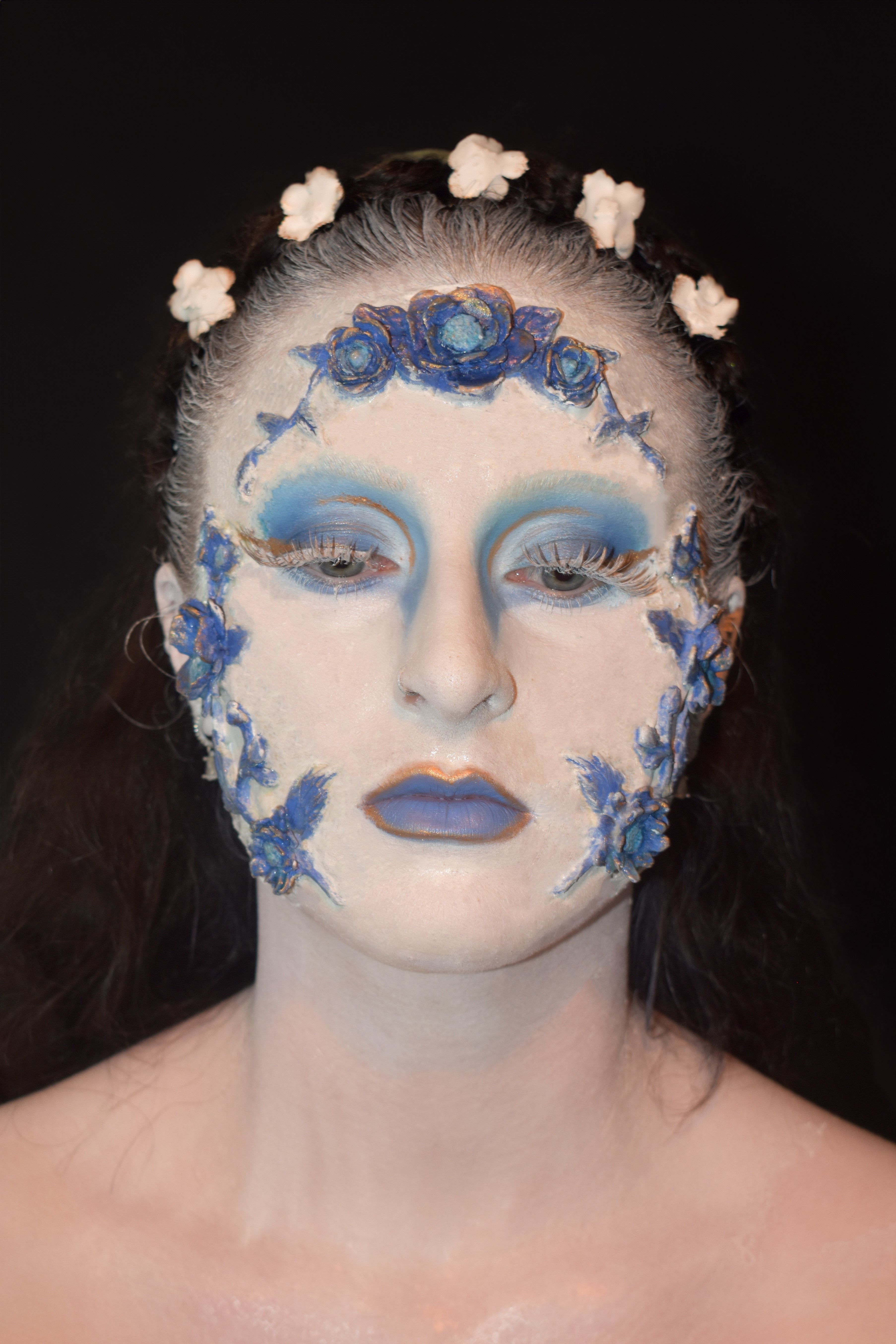 A model wearing make-up my Jodie Clark, white face and blue, patterned with flowers.