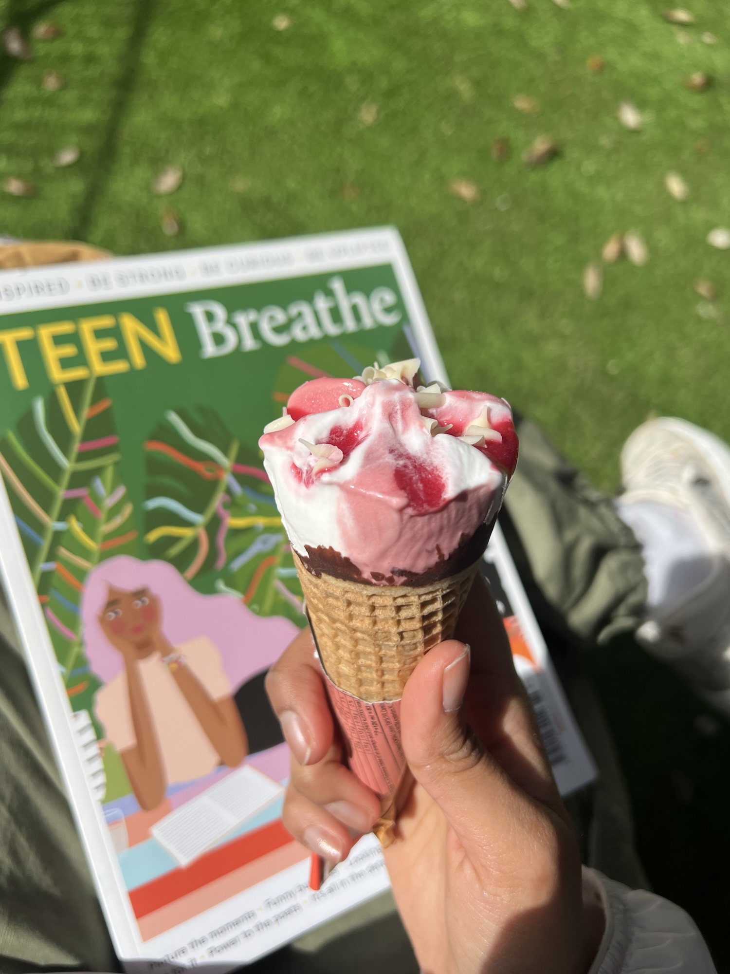 Close-up of a person holding a Cornetto ice cream, with an issue of a publication entitled "TEEN Breathe" in the background.