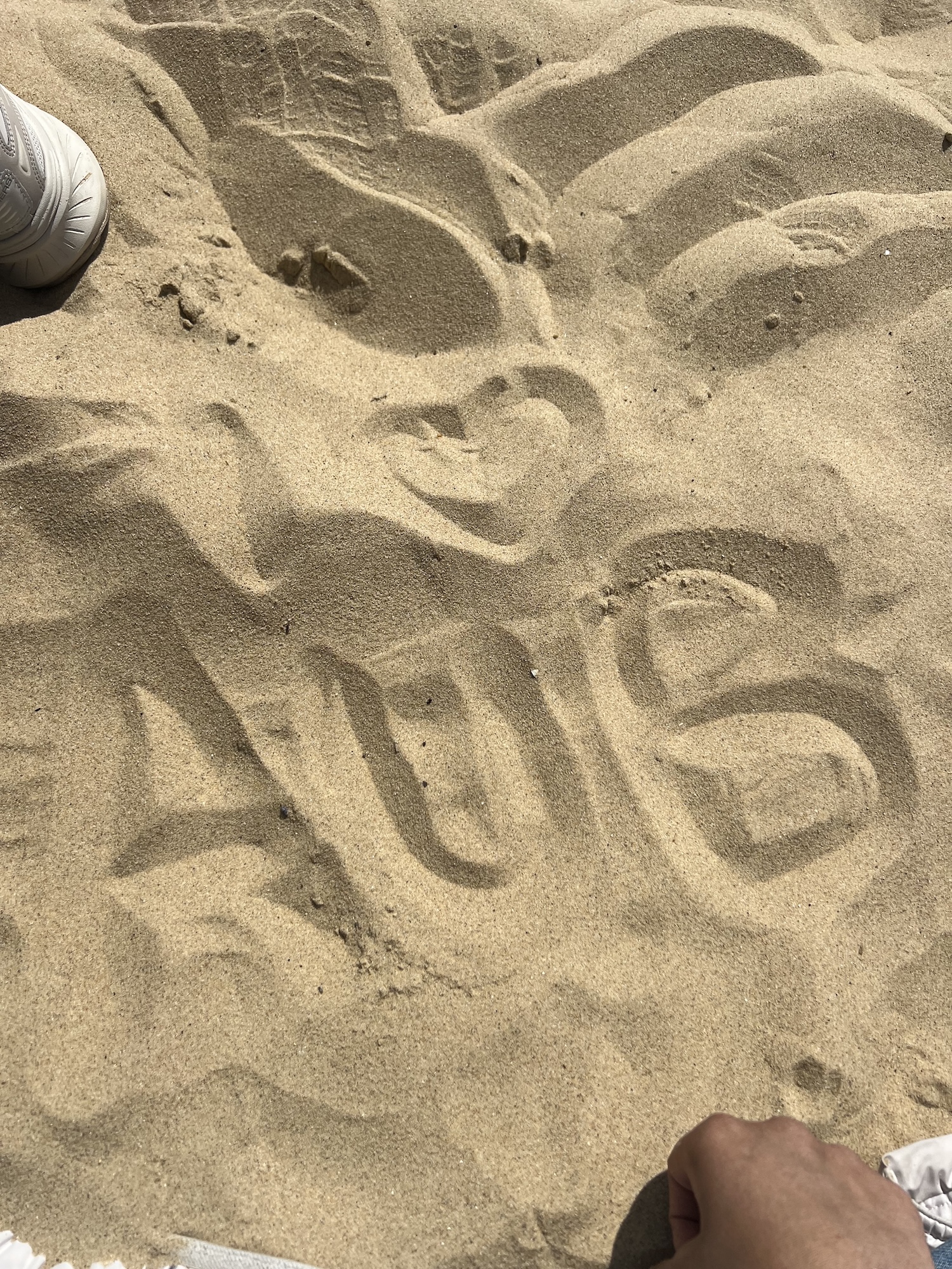 The letters AUB with a love heart above drawn in the sand on Bournemouth Beach.