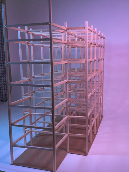 Wooden geometric grid structure with rectangular compartments arranged in rows, illuminated by purple and blue lighting.