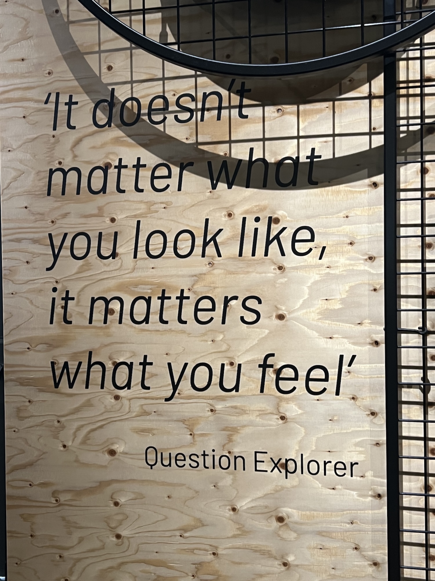 Black text on light wood wall reads "It doesn't matter what you look like, it matters what you feel" with metal stairs visible on right.