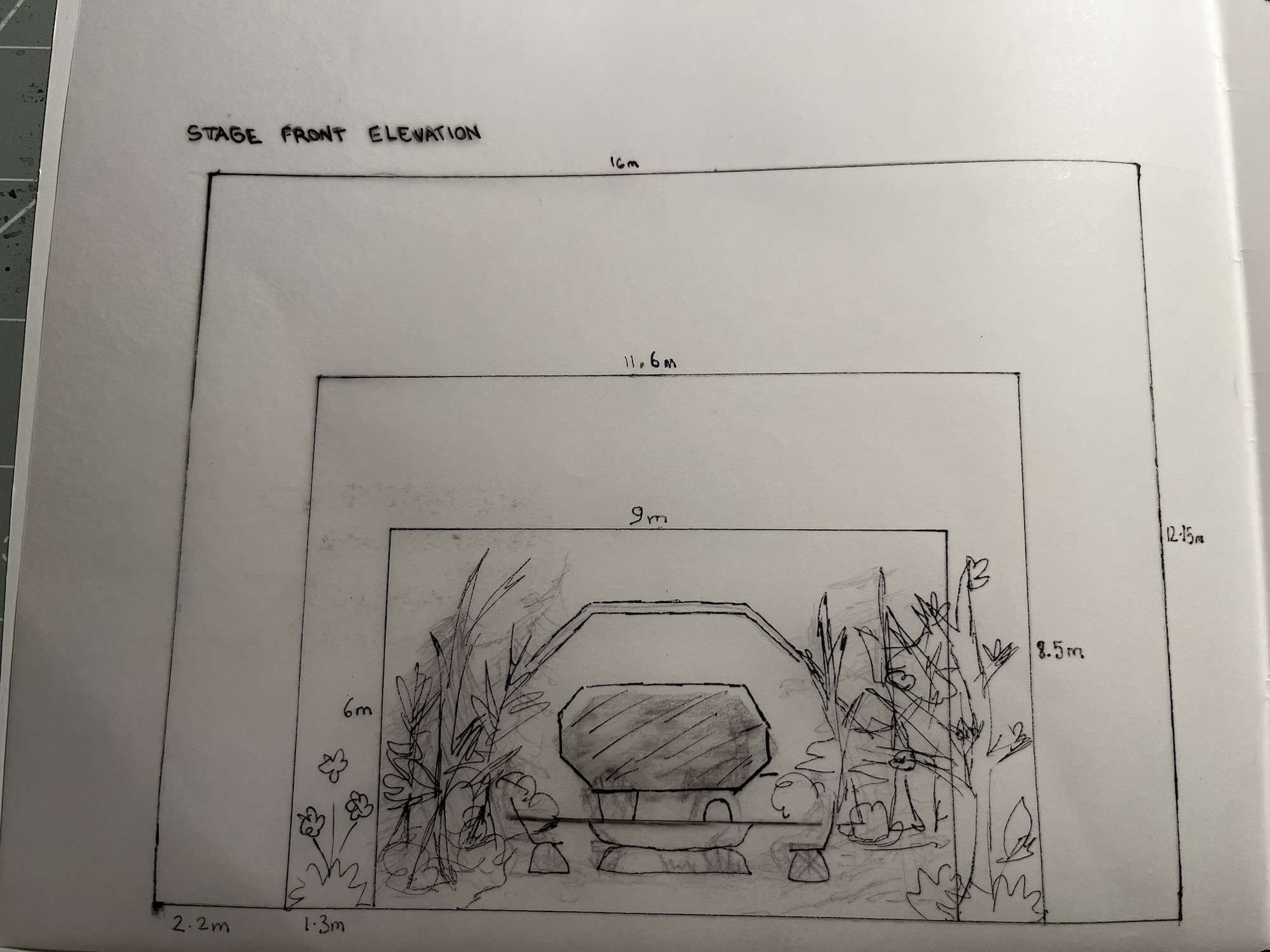 A hand-drawn stage front elevation showing a central podium framed by plants and stepped rectangular outlines, with measurements marked around the sketch on white paper.