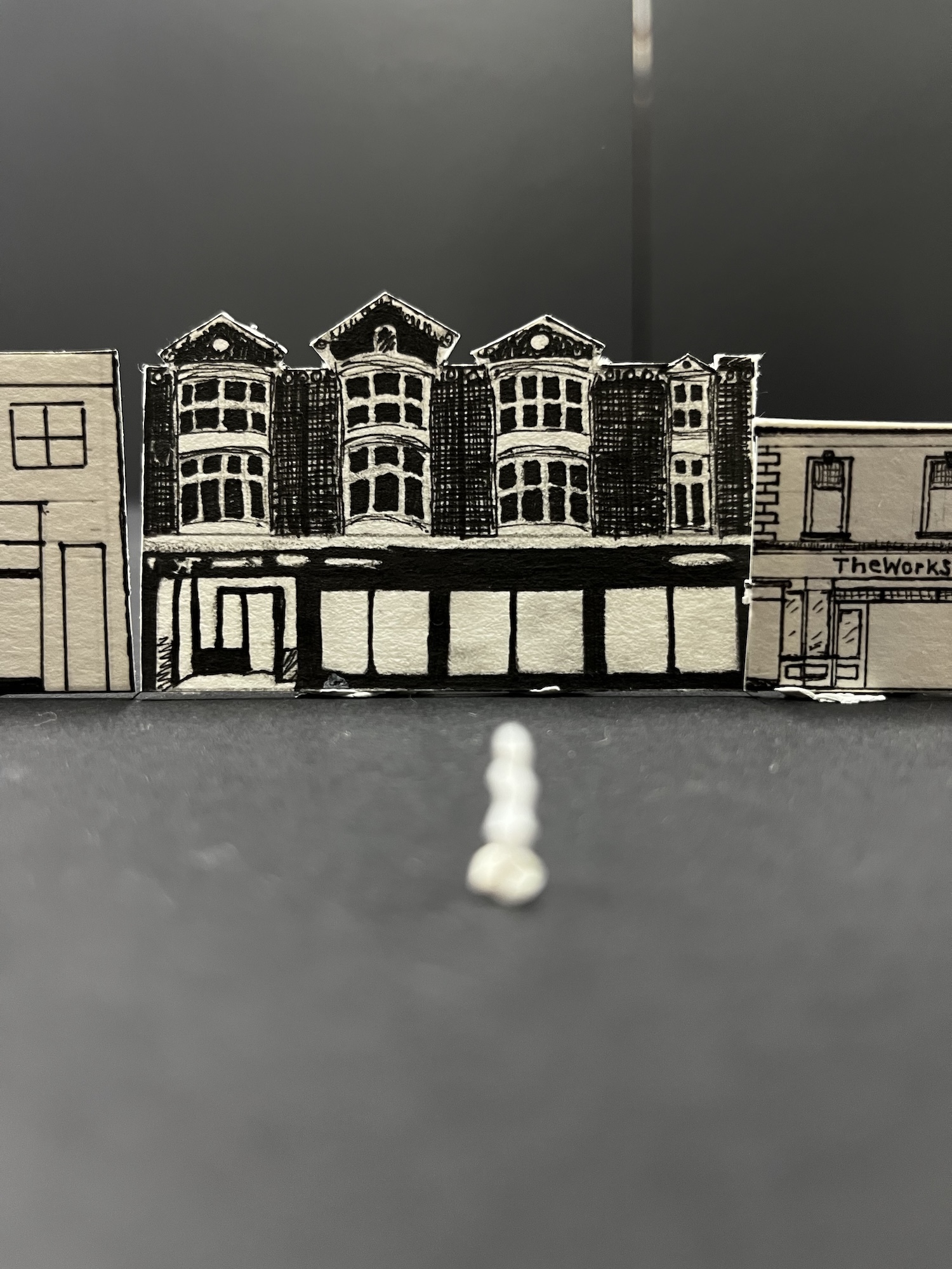 Hand-drawn illustration of Victorian terraced houses with bay windows on white paper, displayed on dark grey surface.