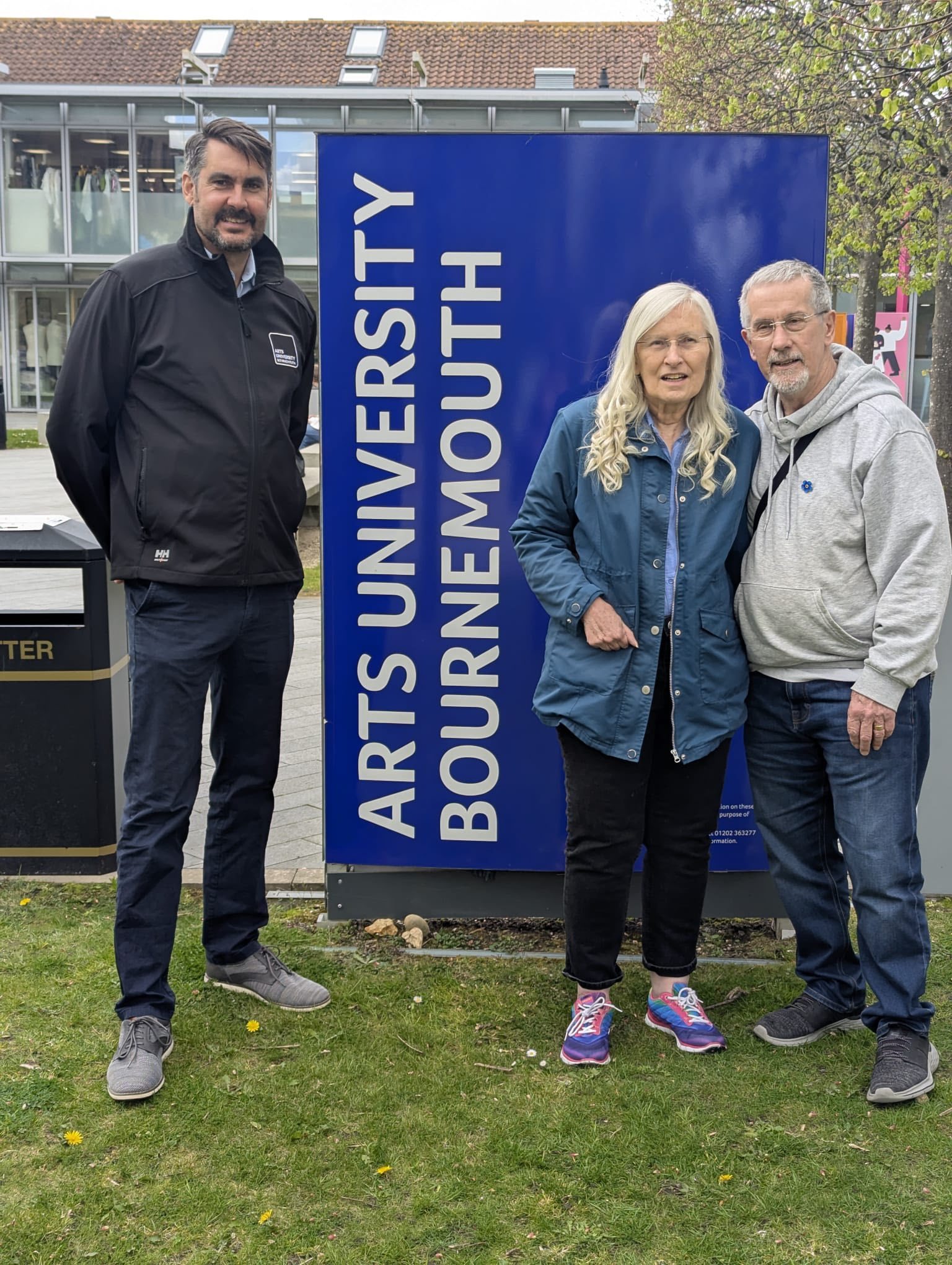 Julia and her husband stood by Tom Marshall in front of a blue AUB sign.