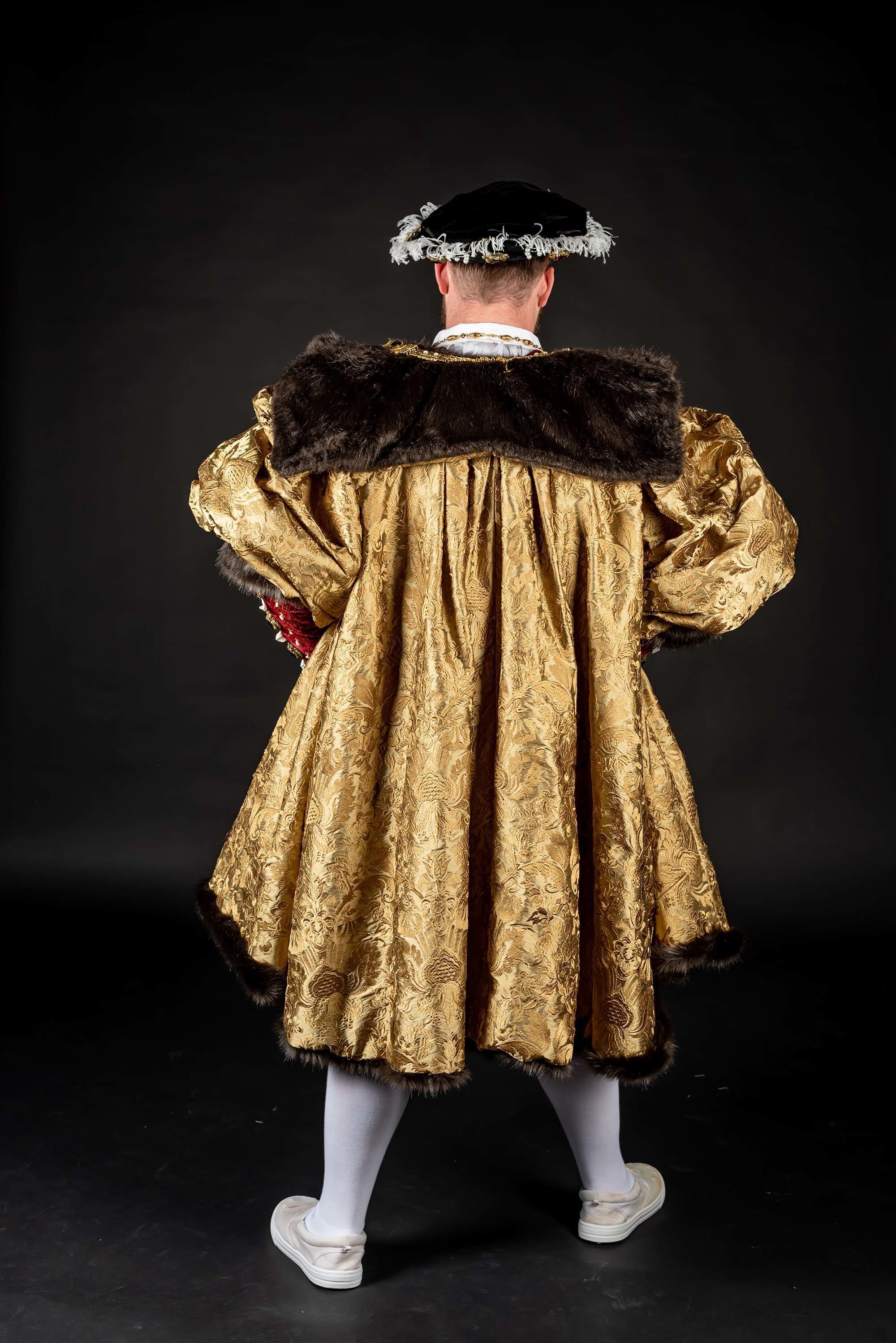 Portrait of a model standing with their back to the camera wearing a gold, fur-collared jacket.