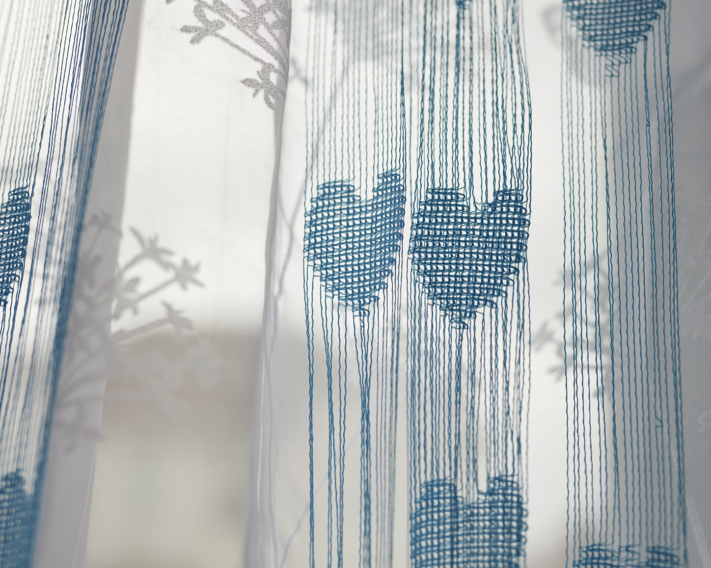 Thin curtains with embroidered love hearts on them.