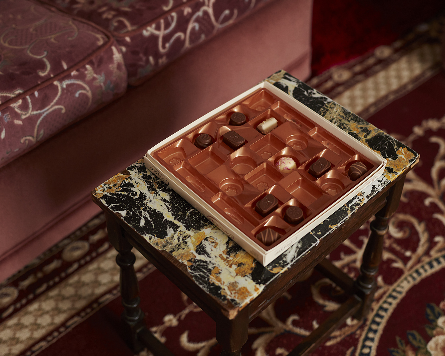 A half-empty chocolate box on a small marbled coffee table.