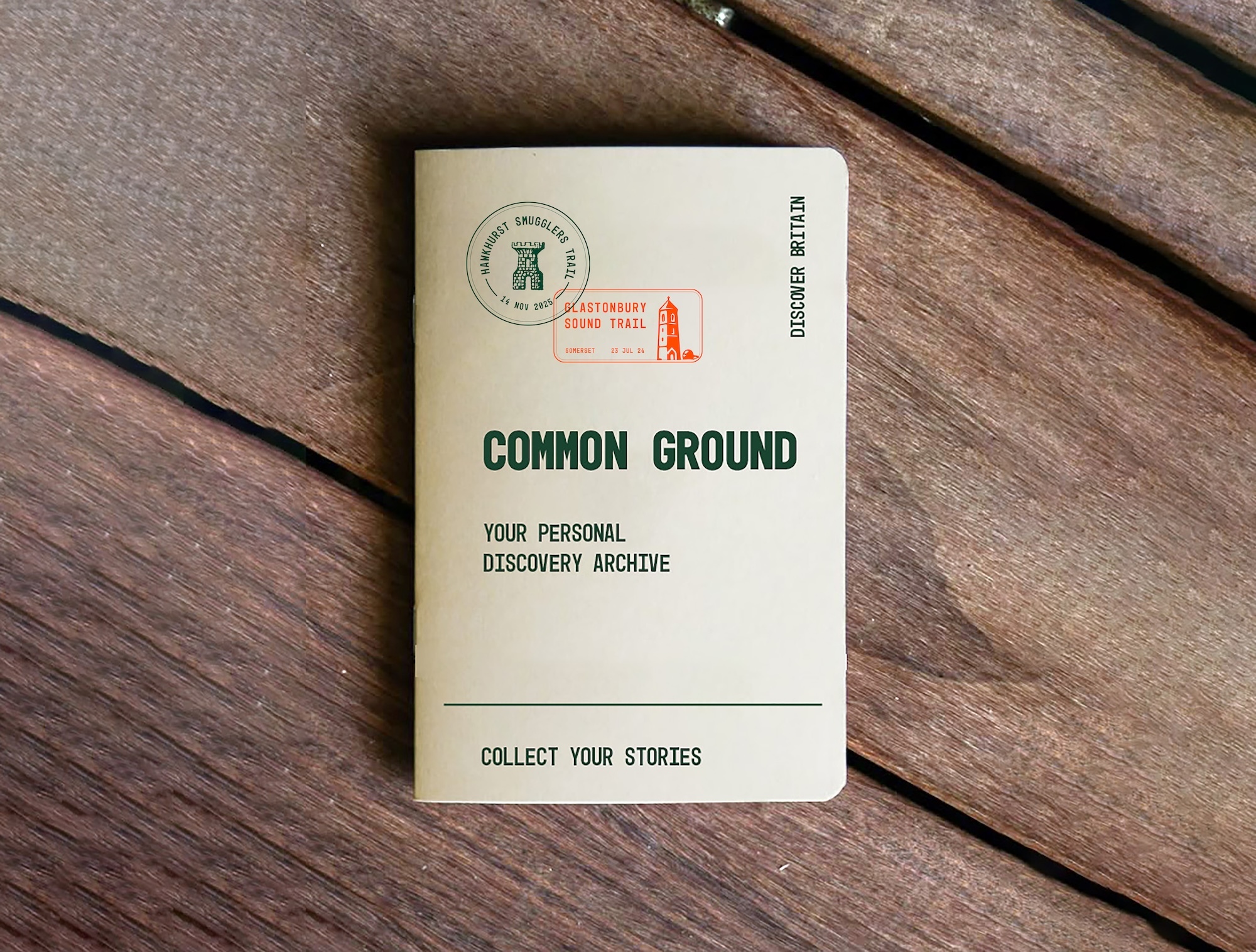 Cream-coloured notebook titled "Common Ground: Your Personal Discovery Archive" with green circular logo and red stamp on wooden deck.