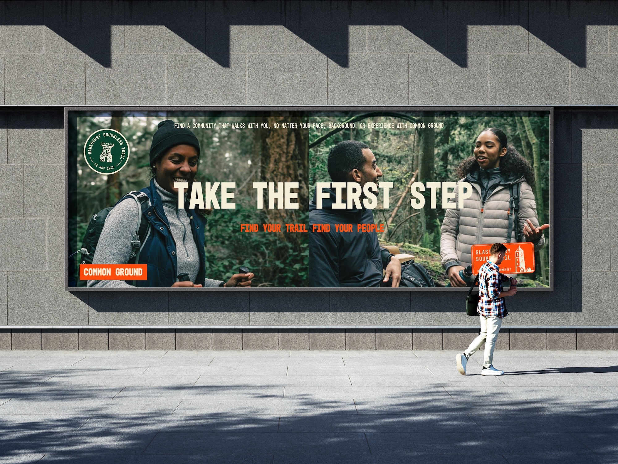 Person walking past large billboard on concrete wall showing outdoor gear advert with "TAKE THE FIRST STEP" text and forest imagery.