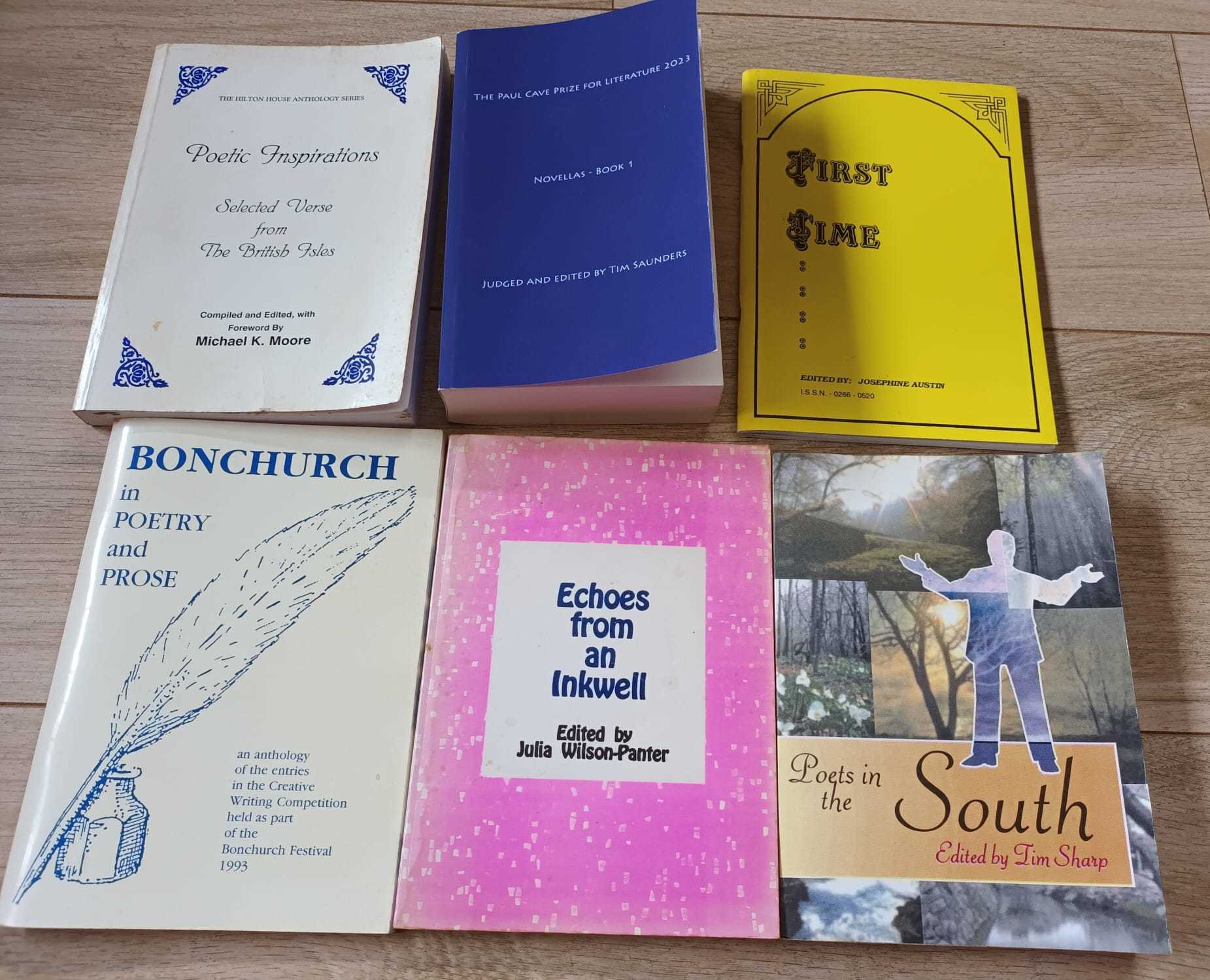Copies of six different anthology books, arranged in two rows of three on a wooden background.