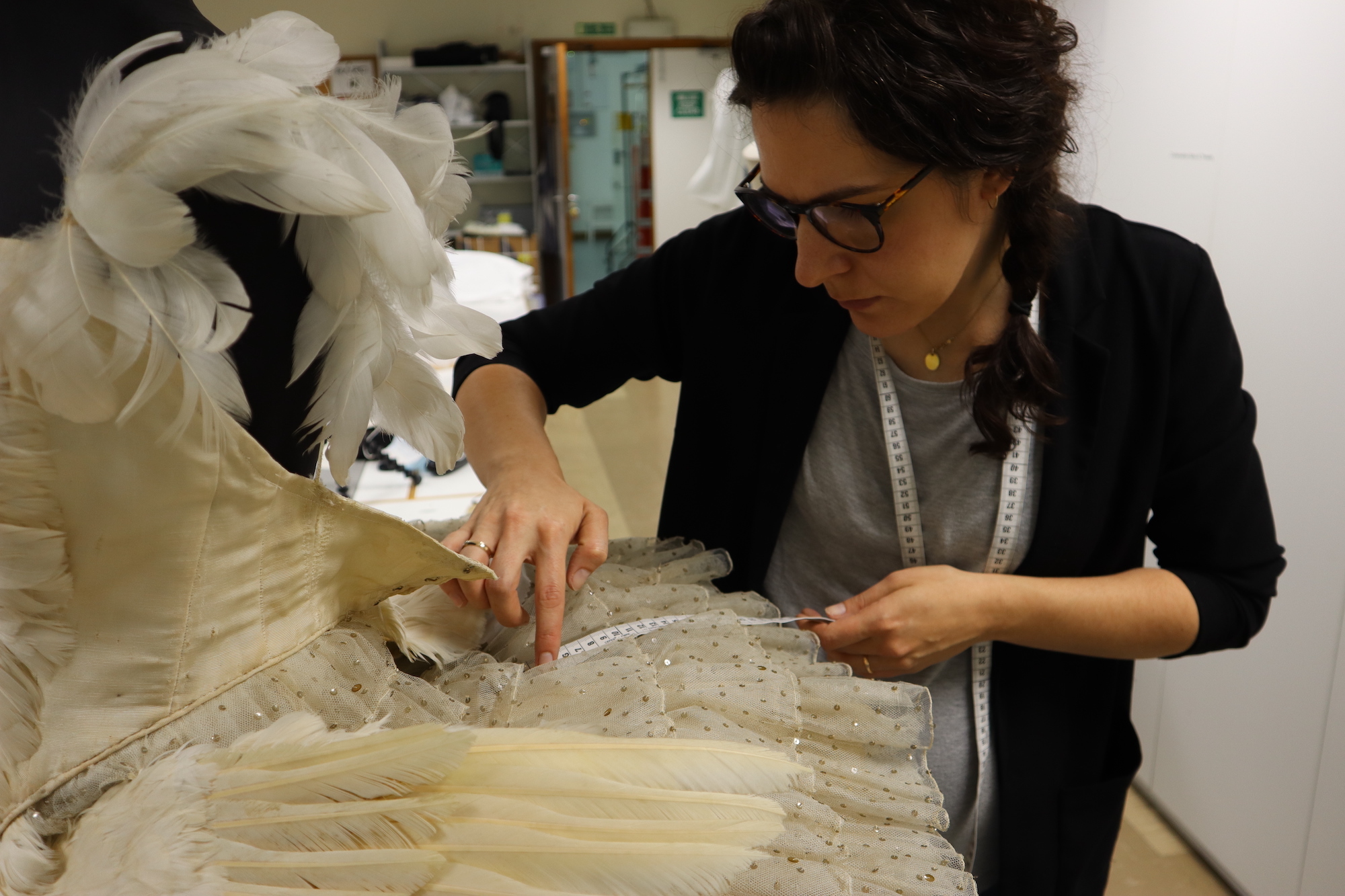 MRes Arts graduate K Kincel measures a piece of fabric with a tape measure.
