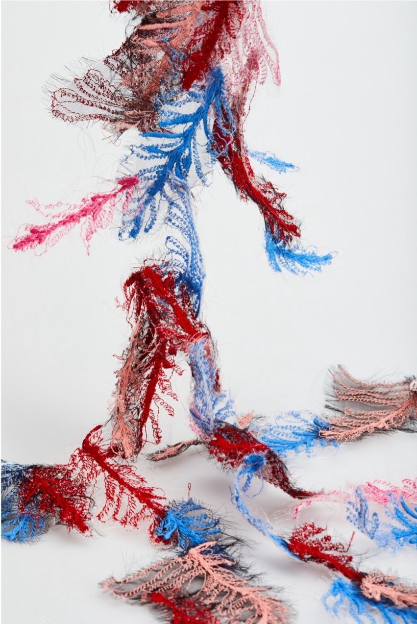 Abstract feathered textiles on a white background, red, blue and pink.