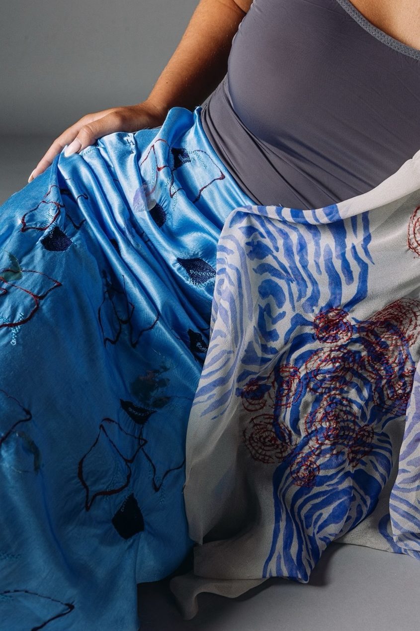 Model wearing a blue, patterned skirt, grey background.
