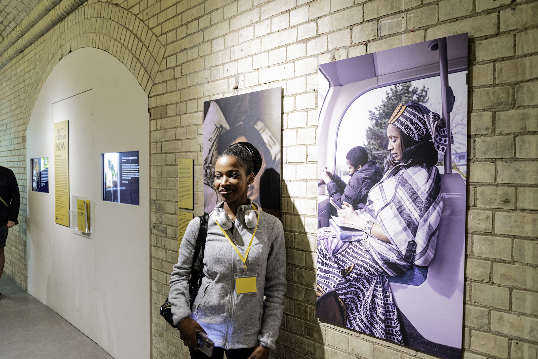BA (Hons) Commercial Photography student K Roberts-Conteh standing next to their portrait at Photo Portrait Now, National Portrait Gallery, London.