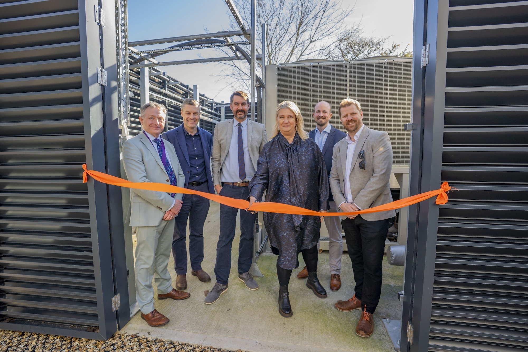 S. Bull, I. Rodger, T. Marshall, L. Mann, D. Blood and N. Cole posing for a ribbon cutting photo at Arts University Bournemouth's air source heat pump site.