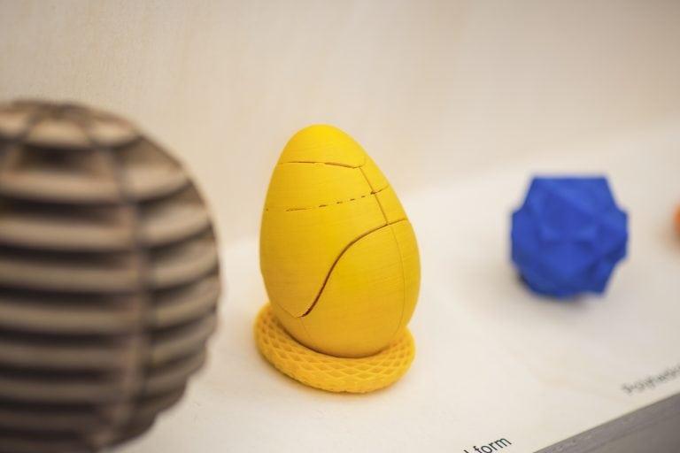 A yellow egg-shaped object sitting in a yellow nest on a shelf.