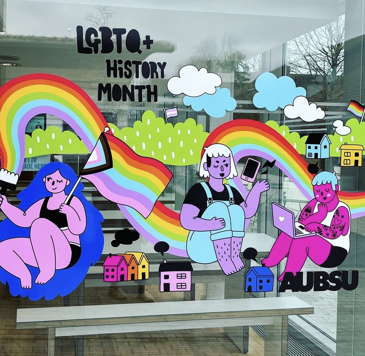 Three colourful characters painted onto a glass surface with a rainbow running all the way through. The words LGBTQ+ History Month are painted above