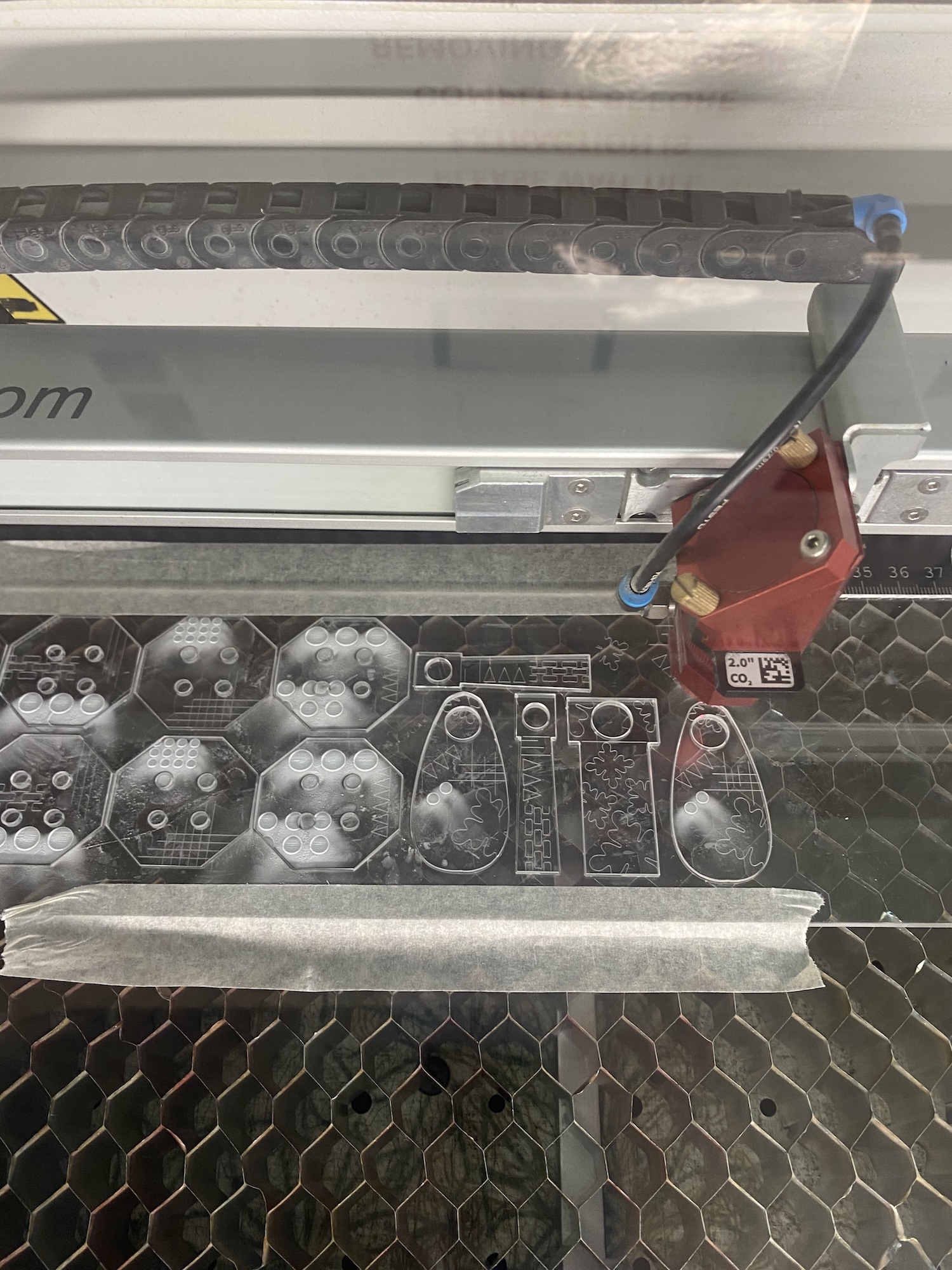 Industrial printing machine with metal cutting templates arranged on perforated metal surface, red mechanical component attached.