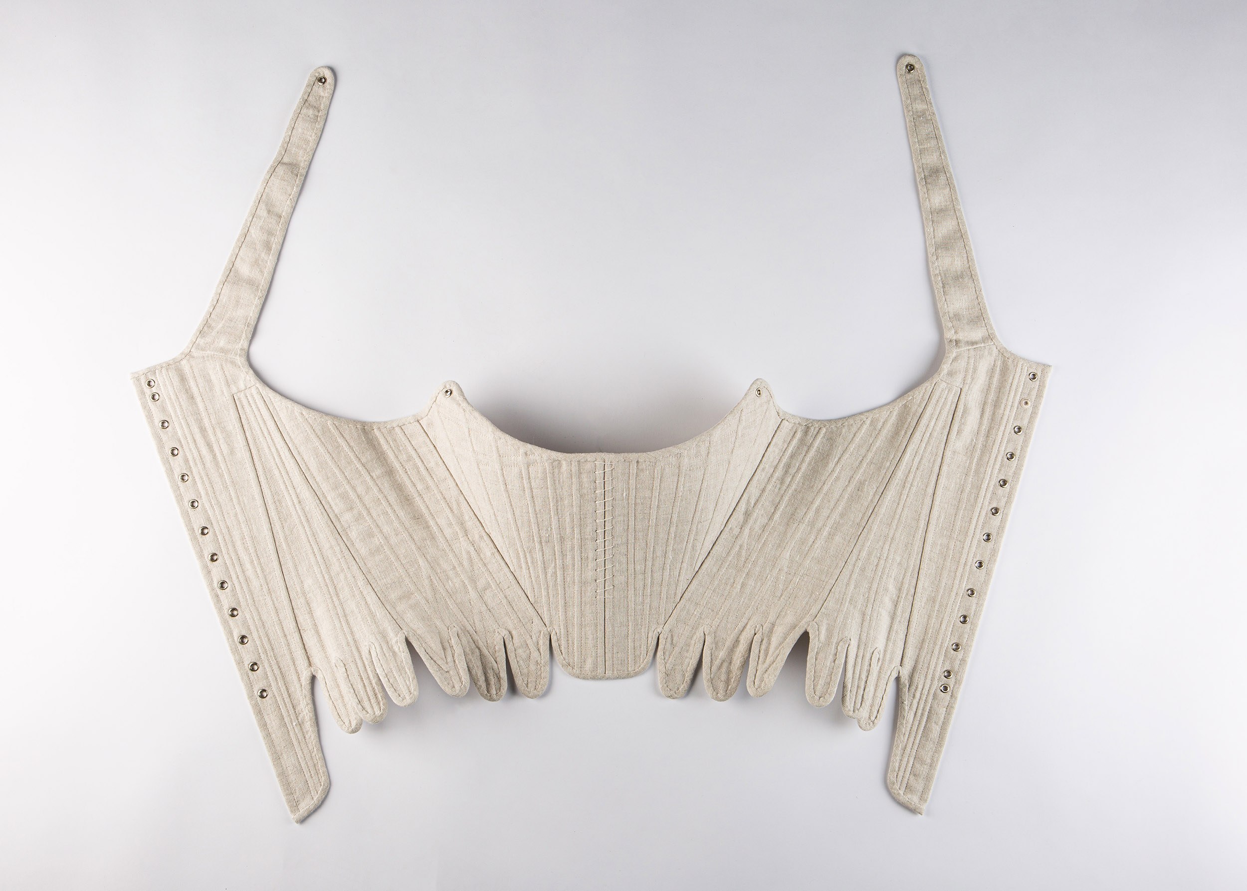 An unlaced corset lying on a plain surface.