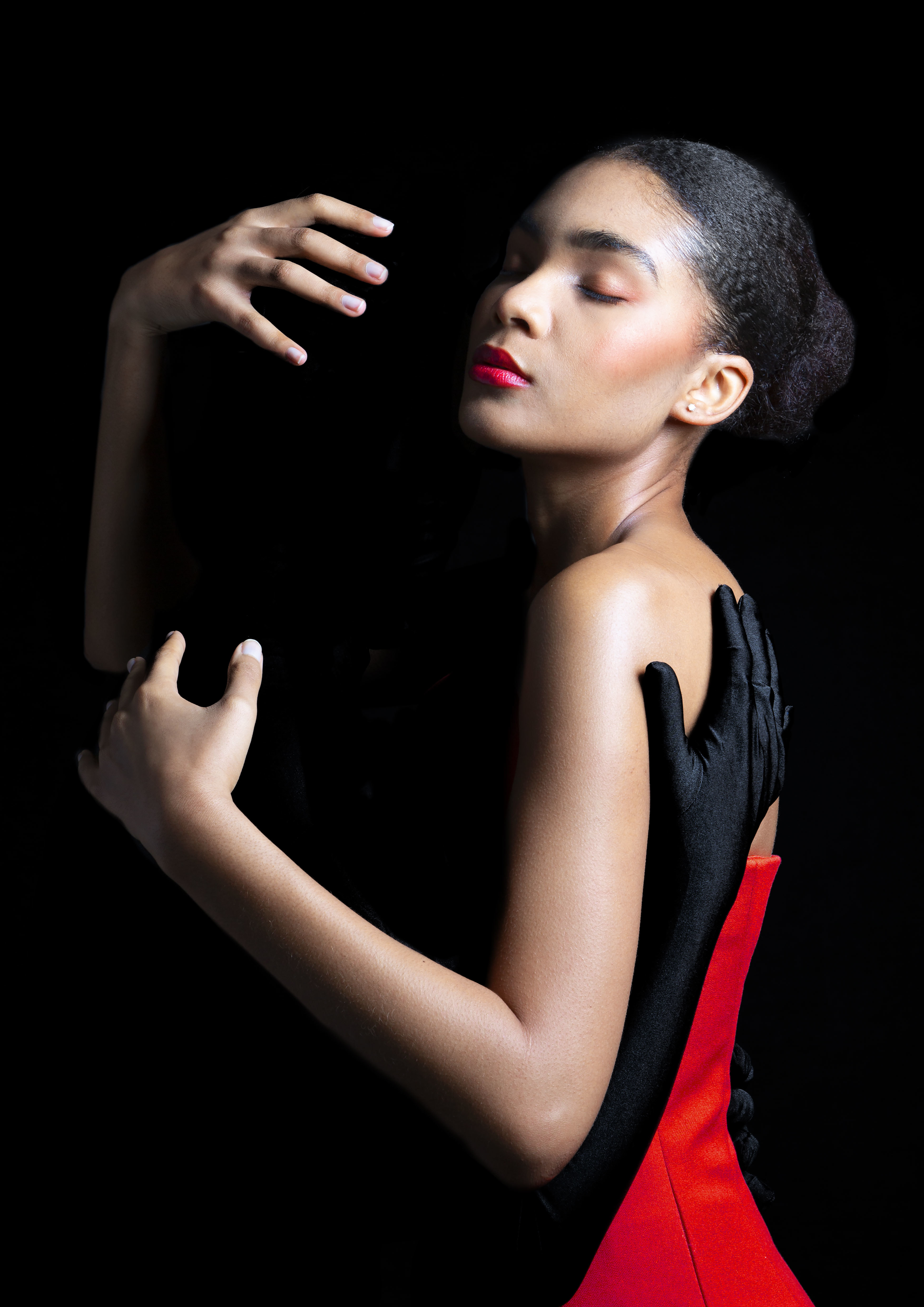 Portrait of a girl embracing a figure all dressed in black, their arms wrapped around one another.