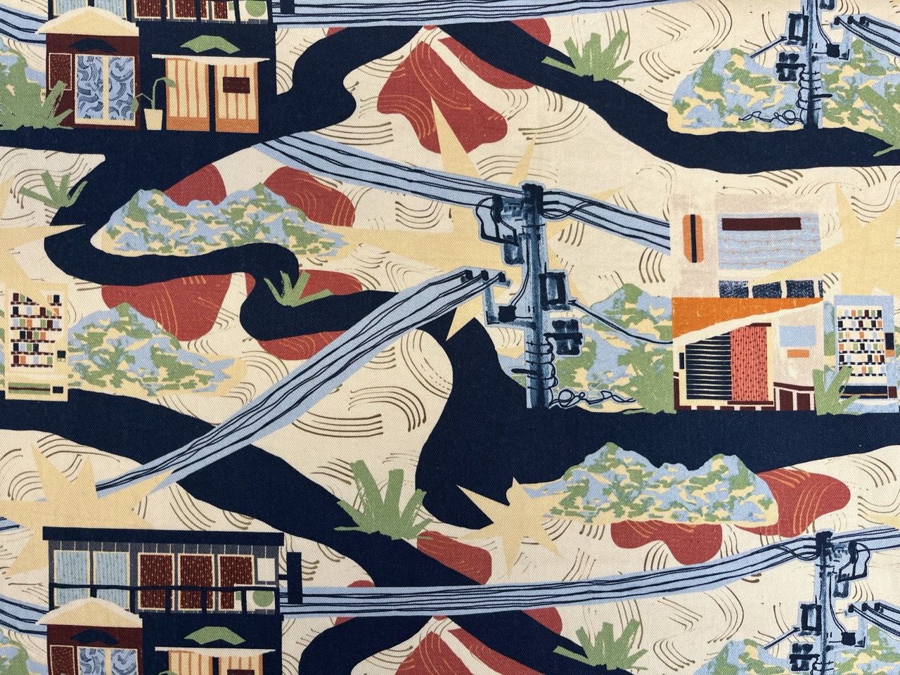 A fabric pattern featuring stylized illustrations of traditional buildings, power lines, and abstract landscapes in a mix of dark blue, red, green, and beige hues. The design incorporates winding shapes and layered textures, creating a vibrant visual effect.
