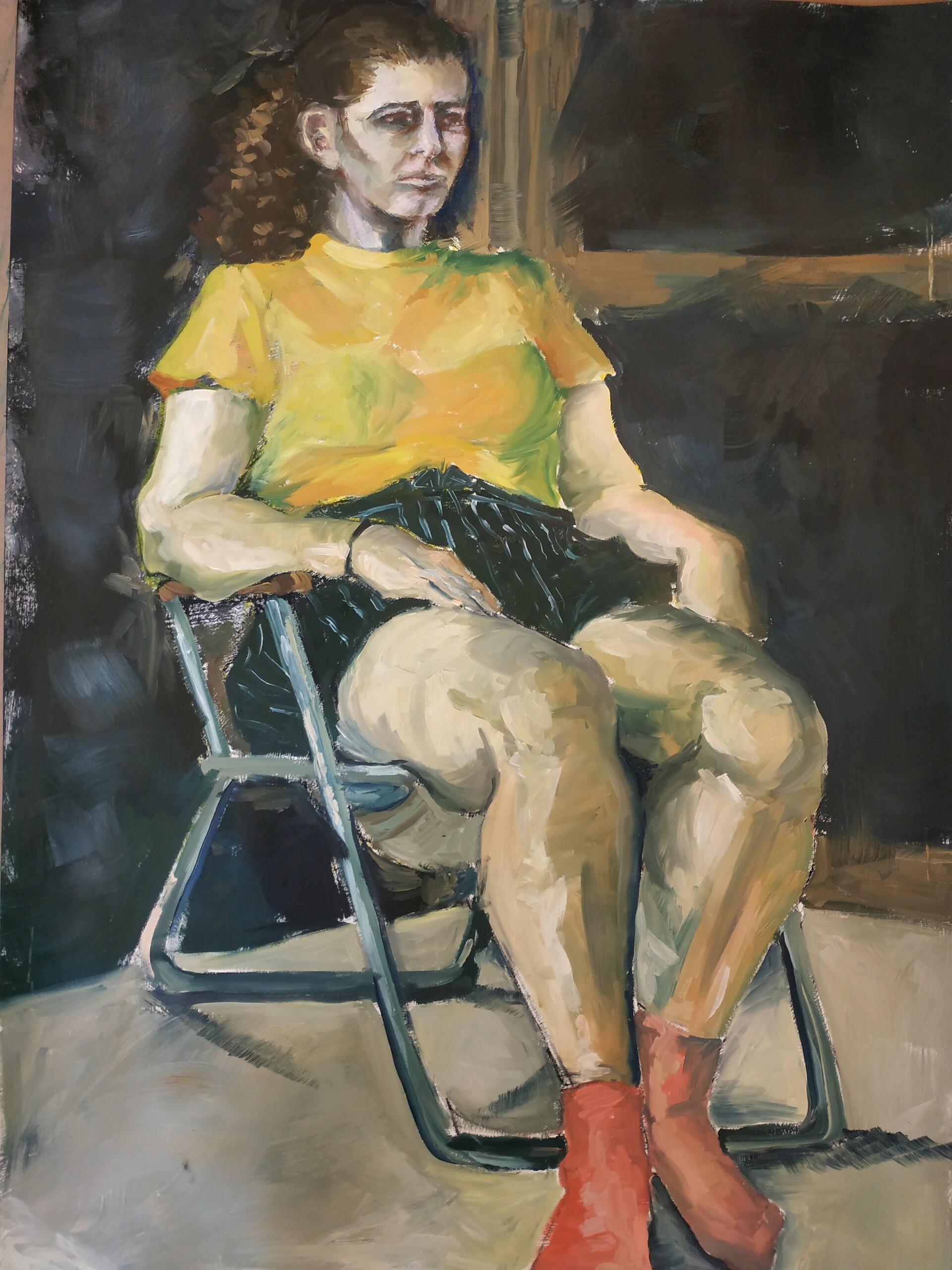 Portrait of a model wearing a yellow top and red socks on a metal chair.
