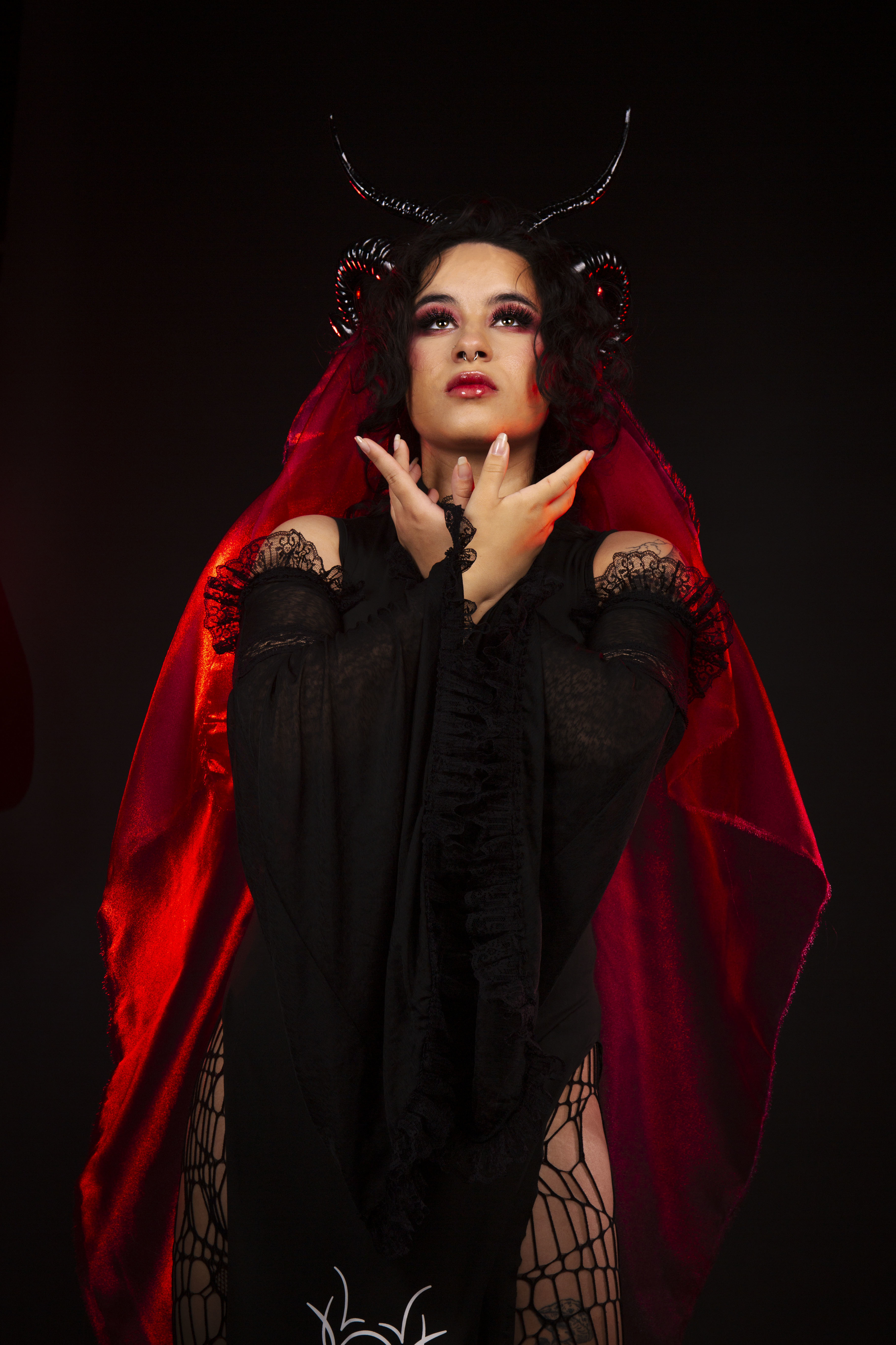Kasandra Georgi dressed as 'Lillith', a devil character with a flowing red cape, black dress and horns.