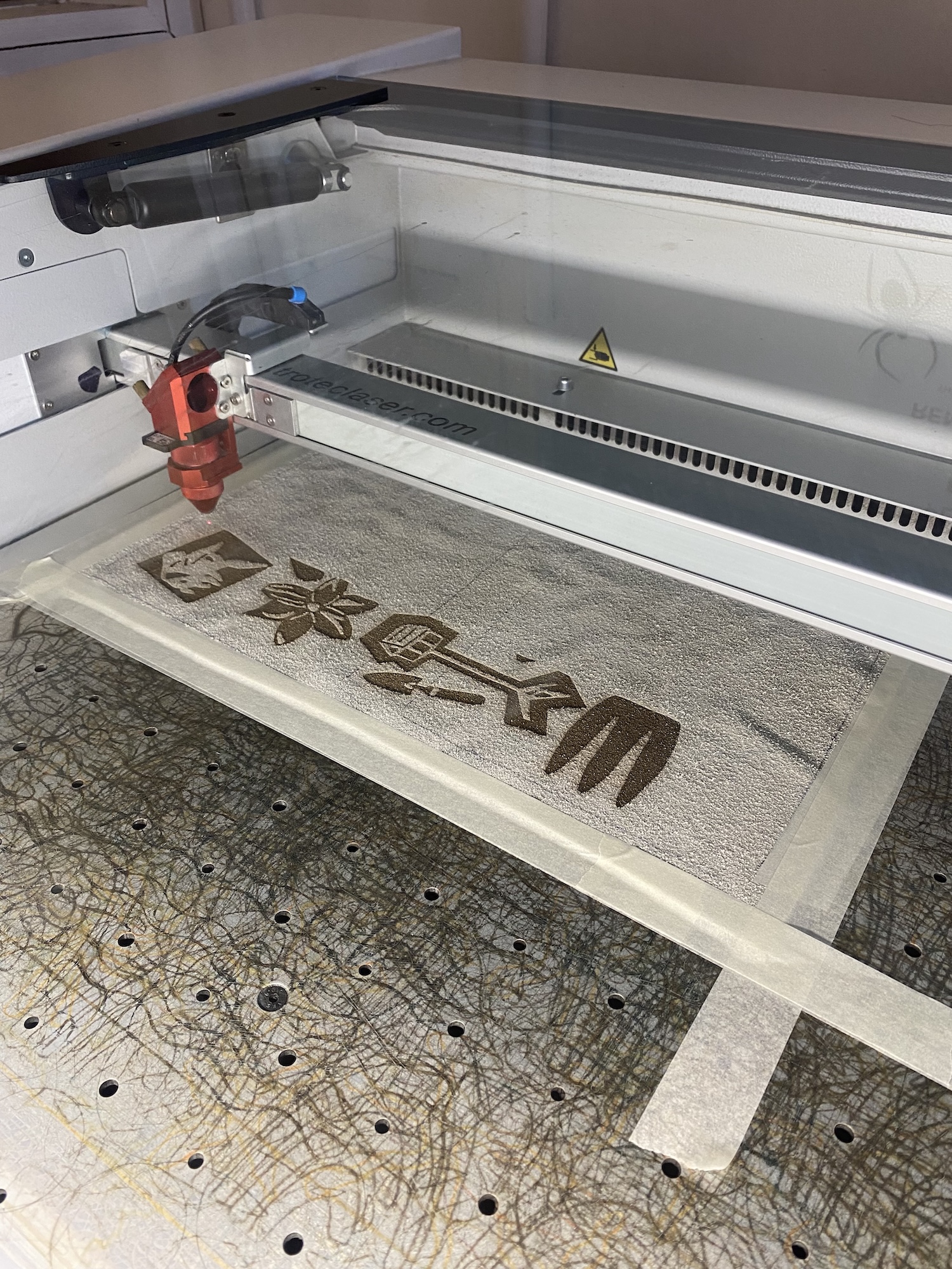 Laser machine burning different floral and garden-inspired designs into a piece of material