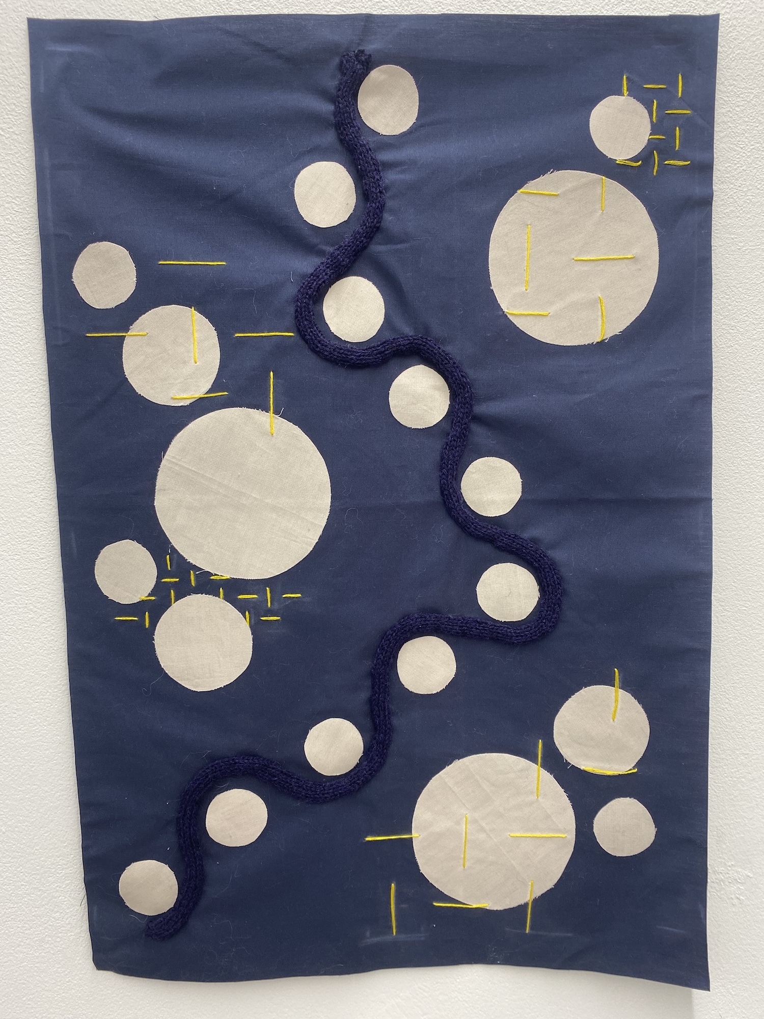Piece of blue fabric with a white circular pattern hanging on a wall on display.