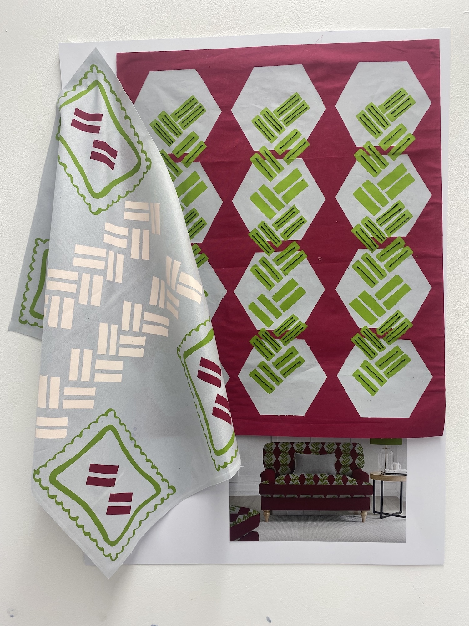 Two samples of fabric on display with versions of an abstract white, green and magenta pattern on both pieces.