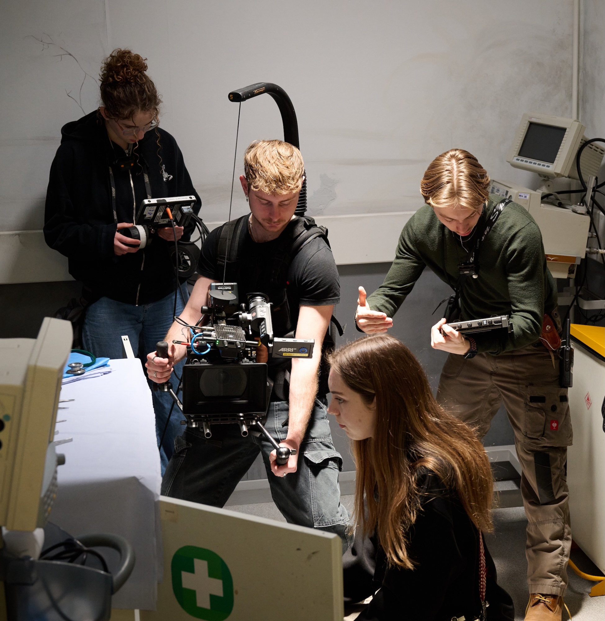 BA (Hons) Film Production crew with professional camera equipment filming in white room with medical cross visible.