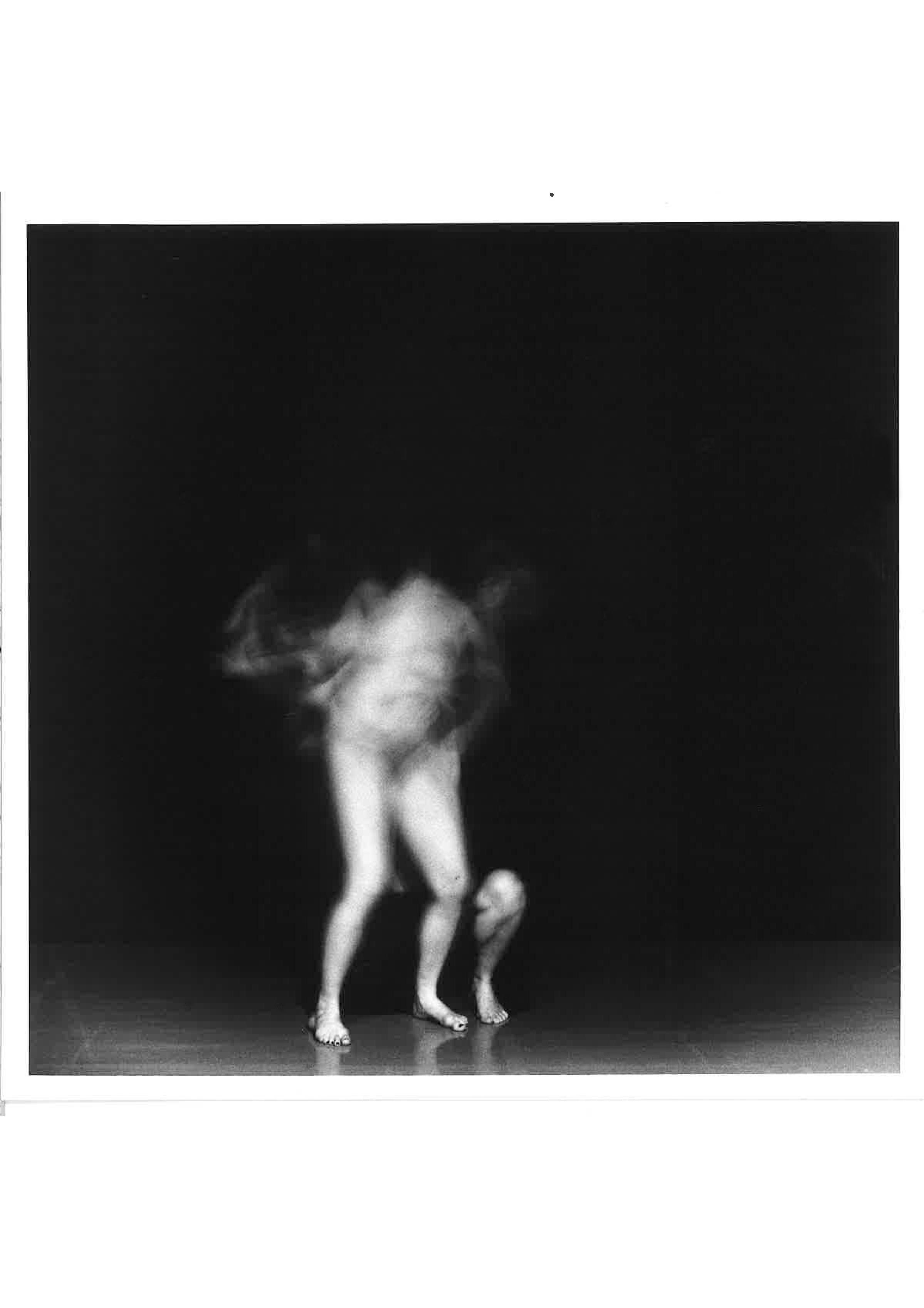Image of a nude figure, blurred from the waist up, and surrounded by darkness.