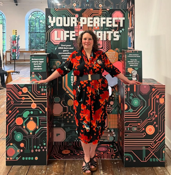 L Moro standing in front of a colourful, futuristic 3D artwork.