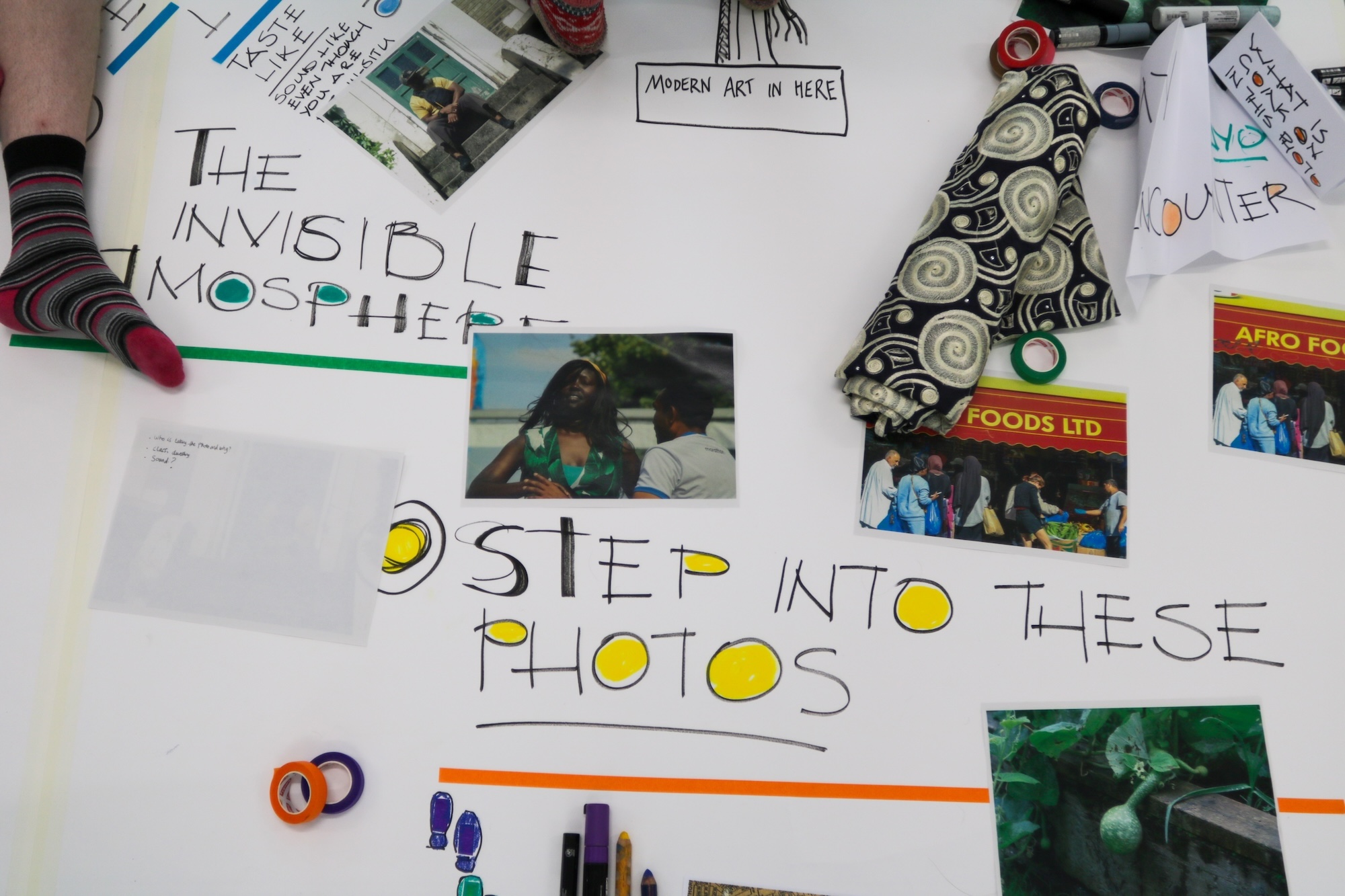 A protest poster about the invisible mosquito is covered with handwritten slogans, photos and drawings on a white surface.