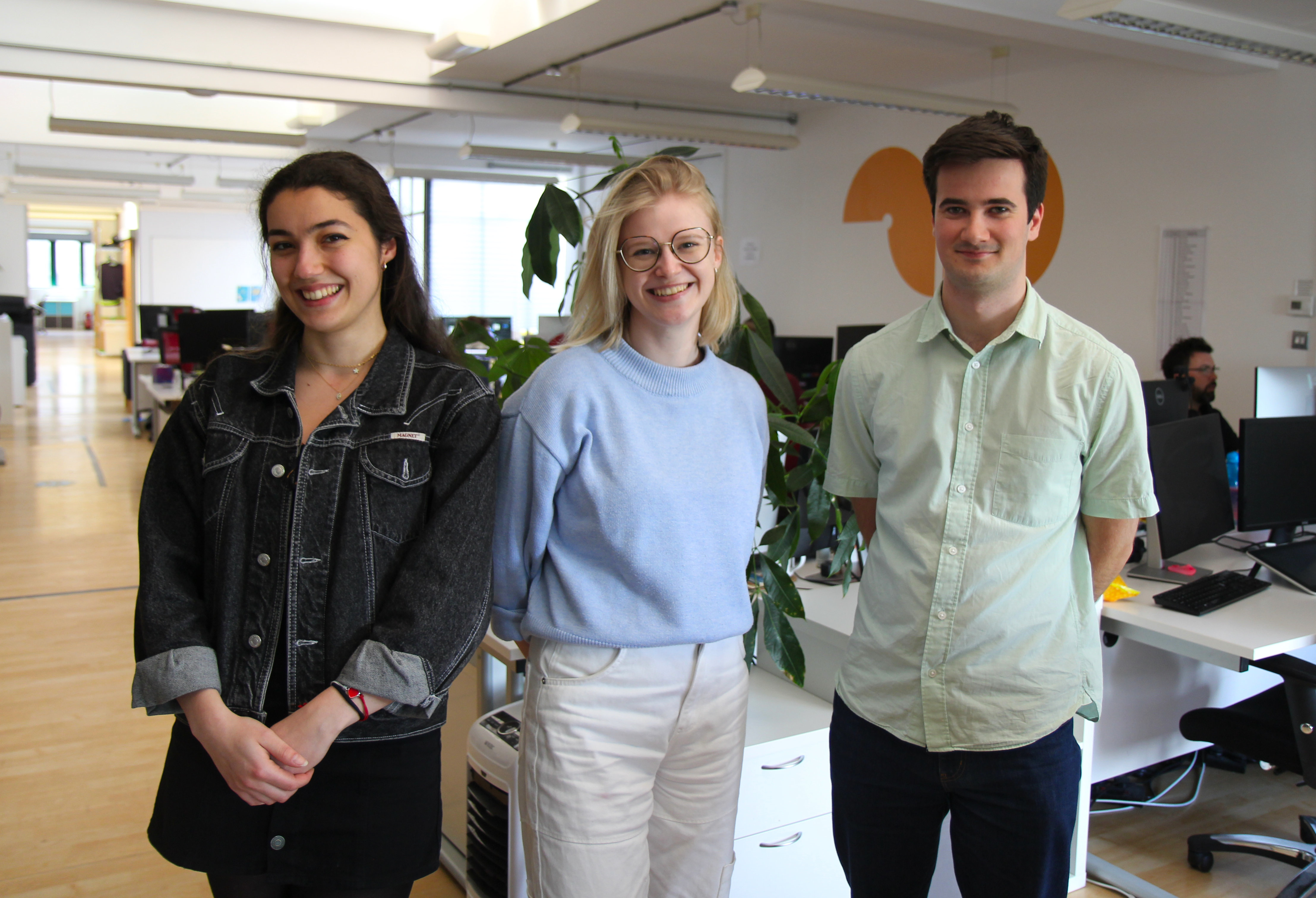 Three people pose for a photo at an animation studio