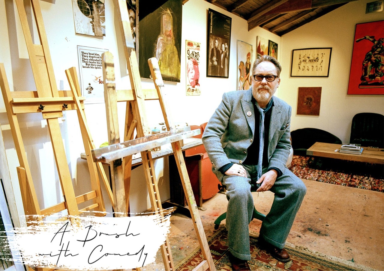 Comedian Vic Reeves sat in an art studio surrounded by painting easels