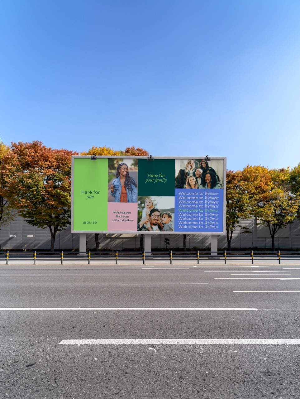Mock-up wellness billboard on the side of a wide road showing people and typography in different colours: green, pink and blue.