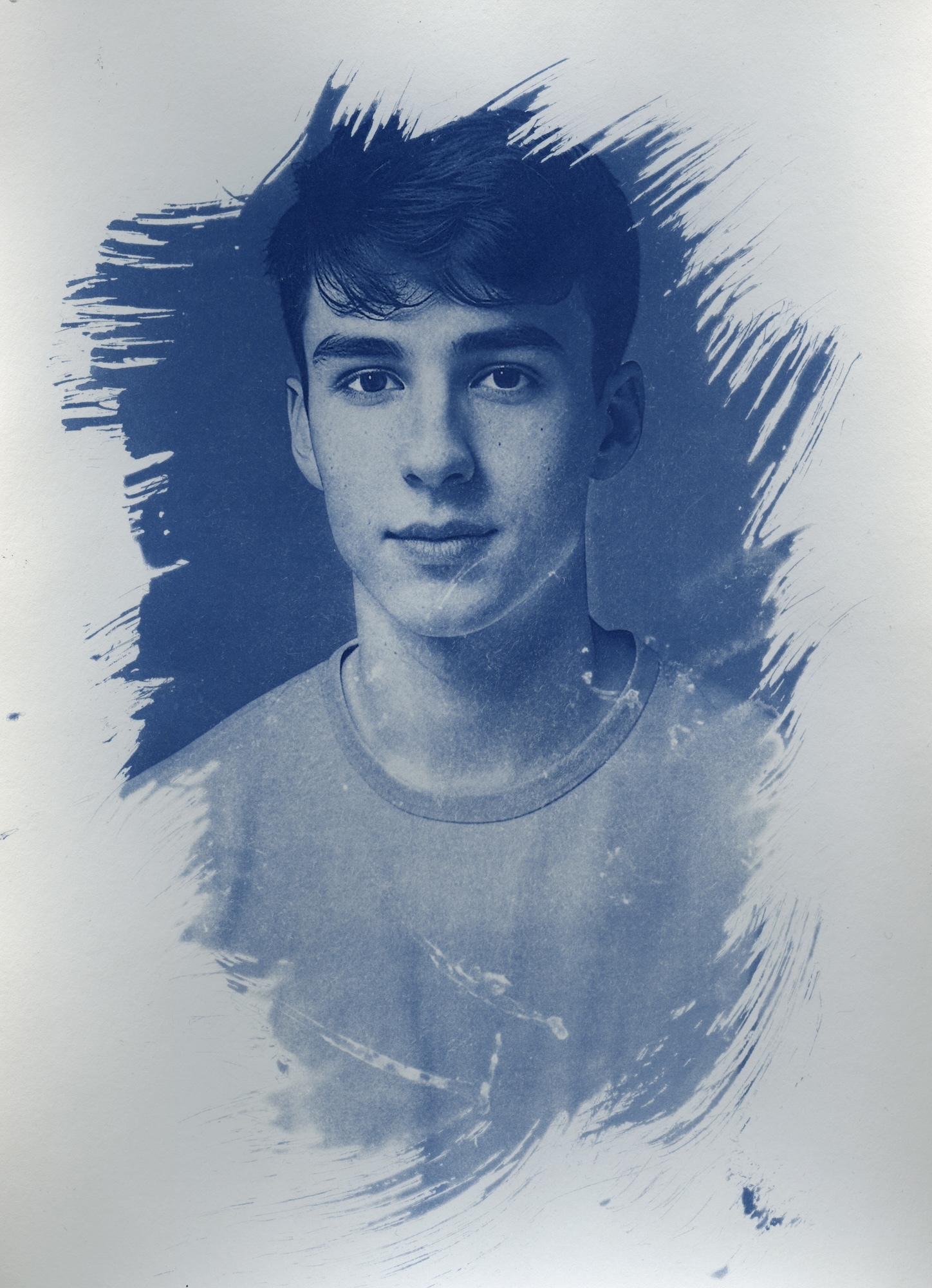Cyanotype head and shoulders photo of a young male, with a brush effect applied to the edges.