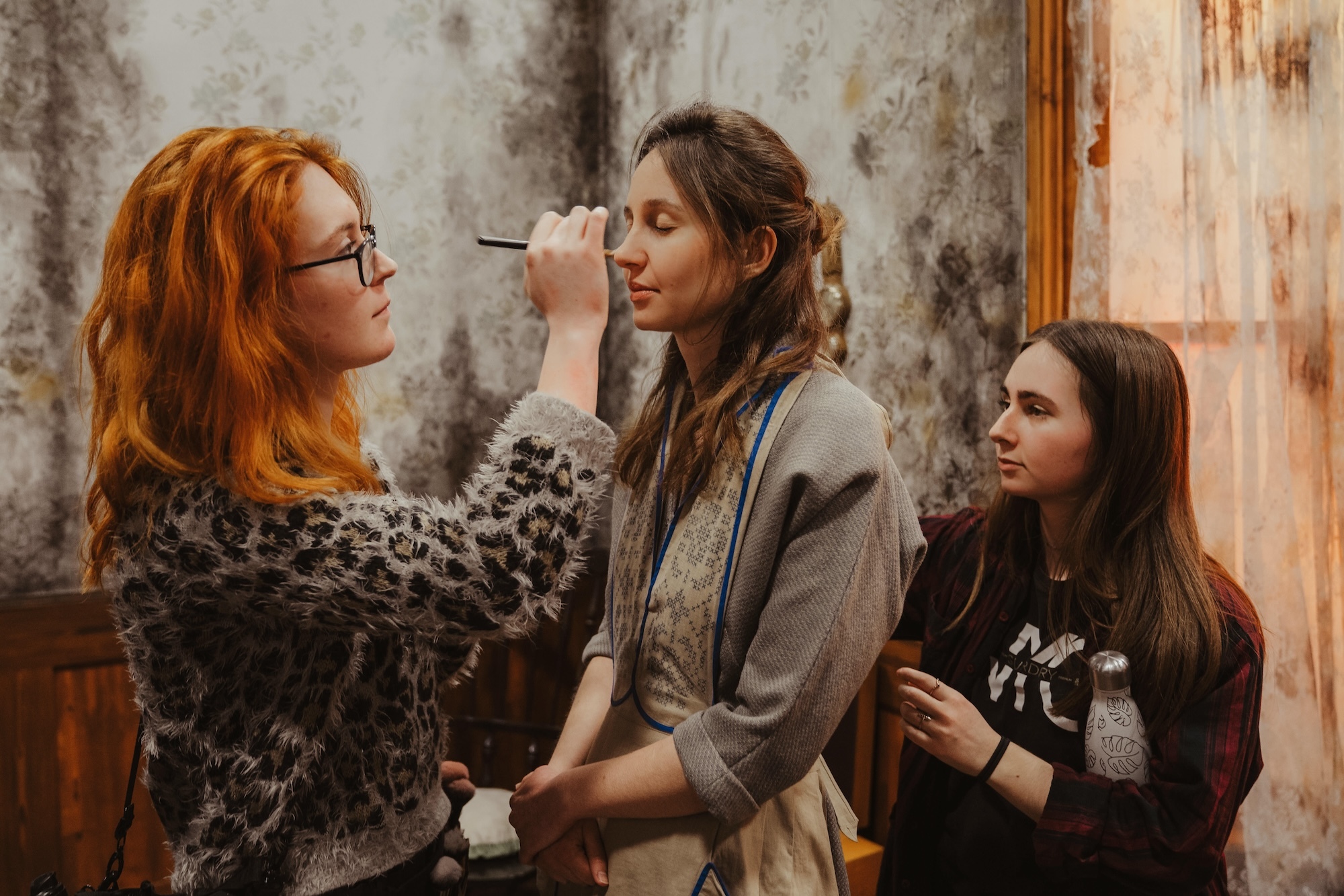 Behind the scenes on Lullaby for the Lost; two members of the hair and make-up team work with an actress on set.