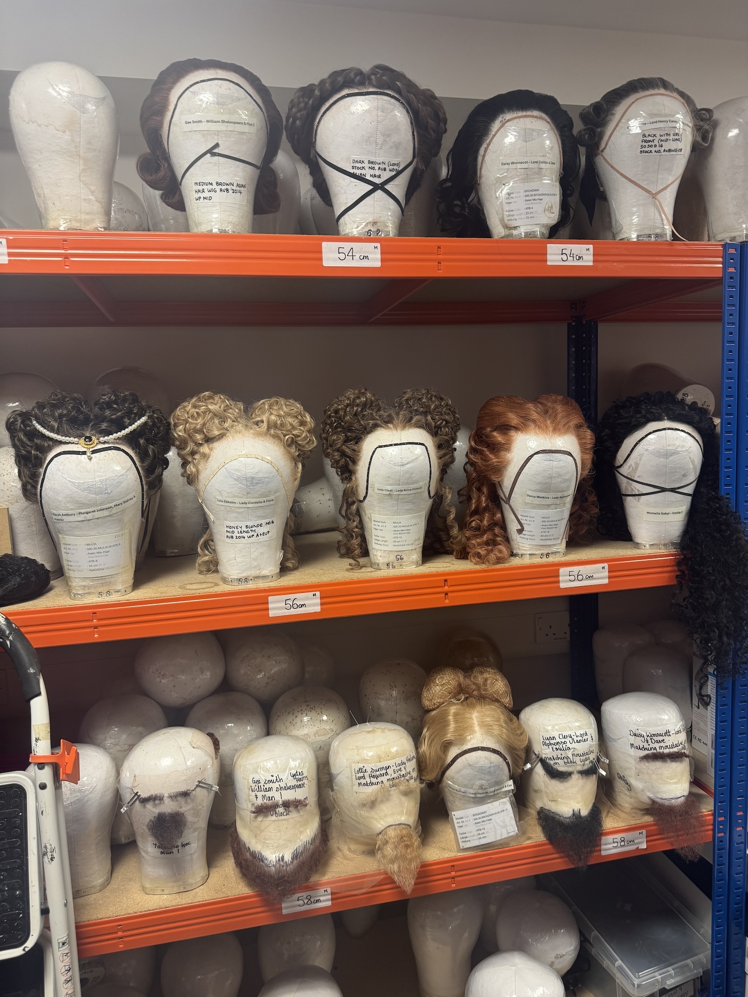 A shelving unit with rows of mannequin heads each wearing a different wig or beard or moustache.