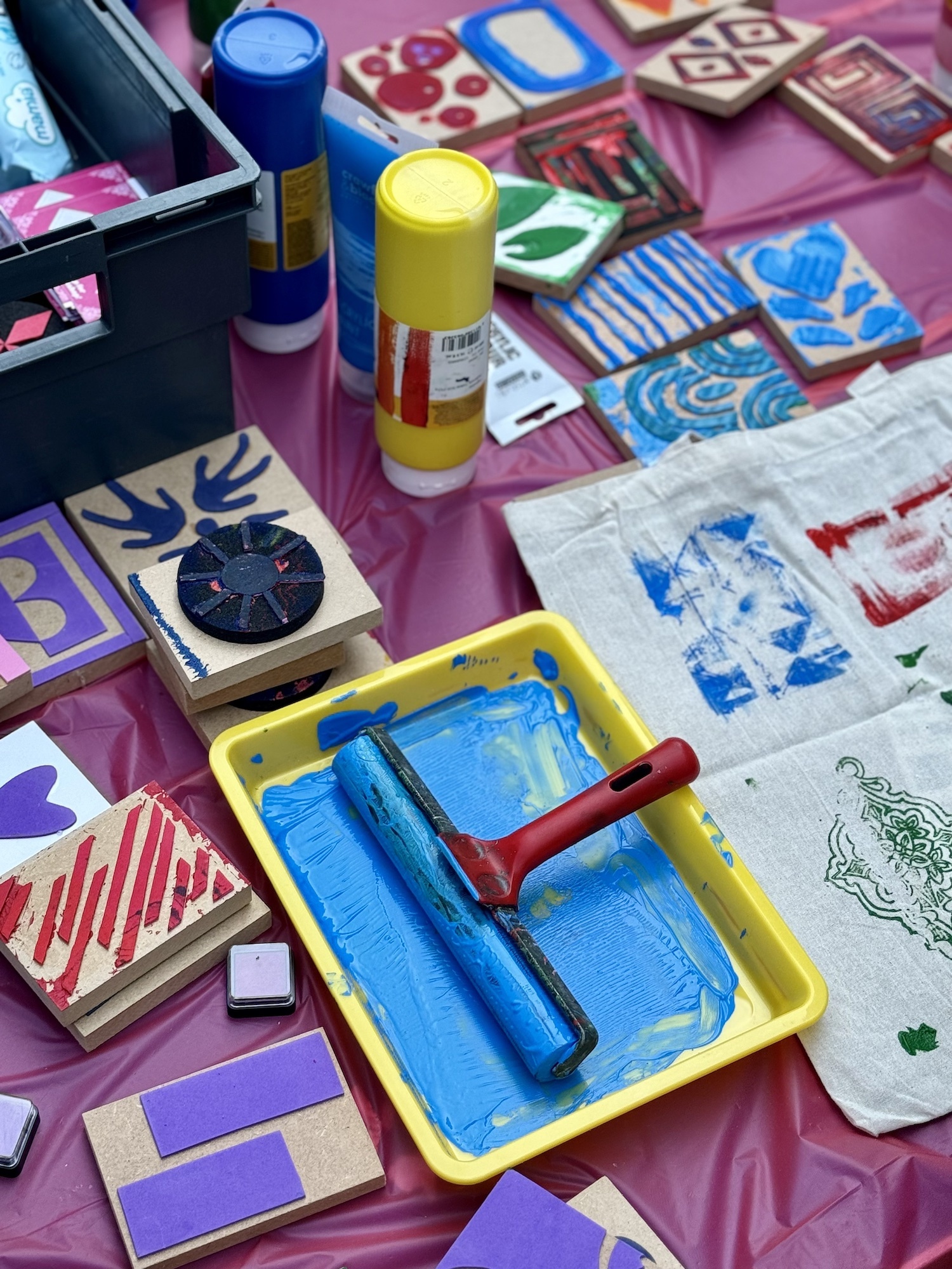 Colourful paints, stamps and other art supplies on a table.