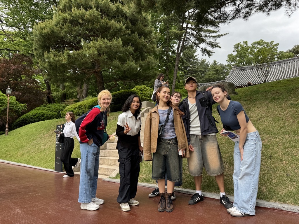 A small group of Arts University Bournemouth students pose for a photo in front of some steps and a grassy bank in Seoul, South Korea.