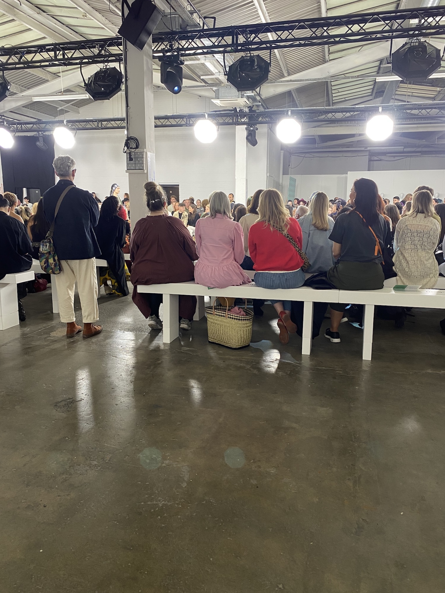 A crowd of people viewed from behind, watching a catwalk show at Graduate Fashion Week 2024.