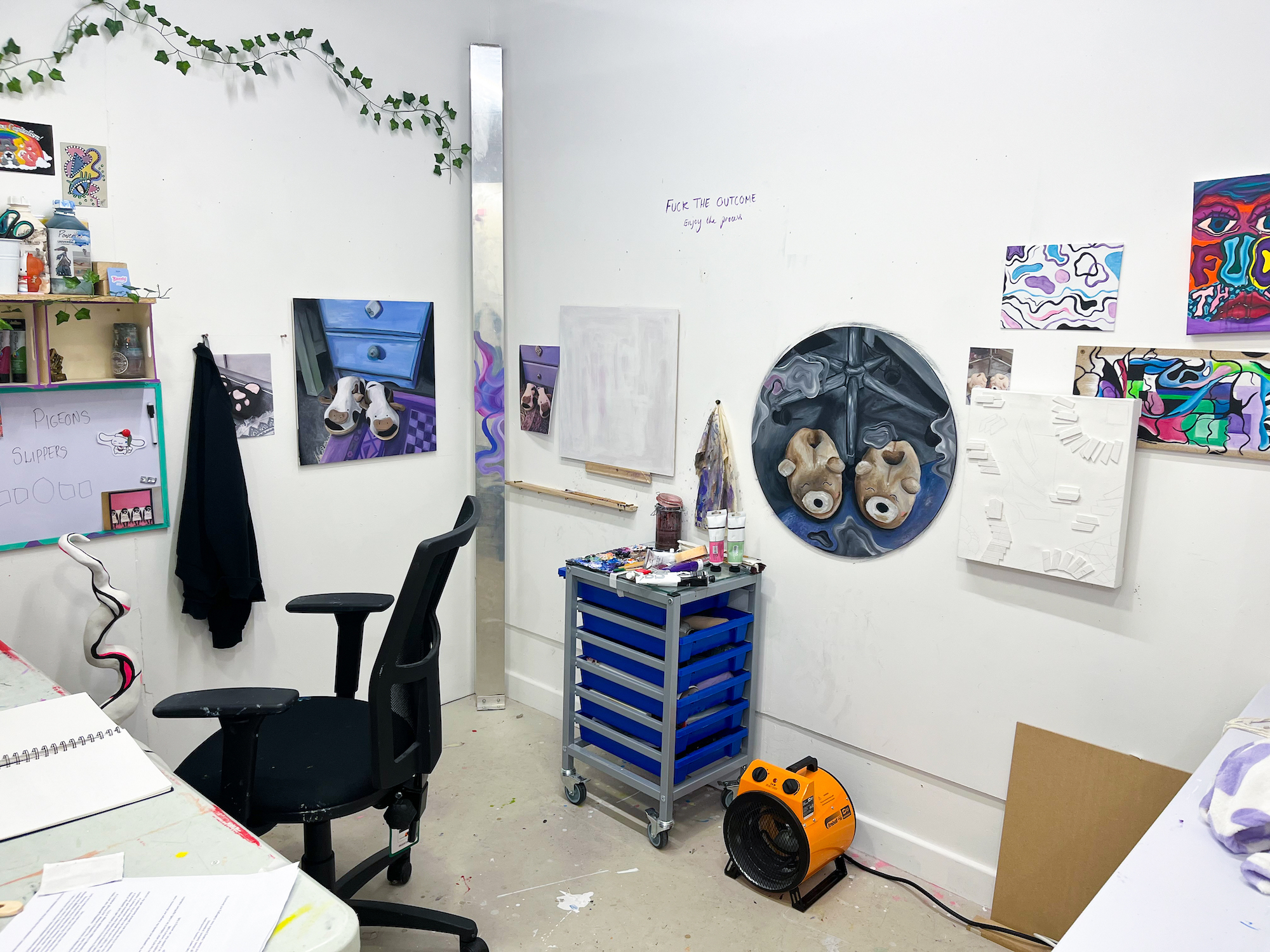 A studio space featuring artworks on the wall and equipment.