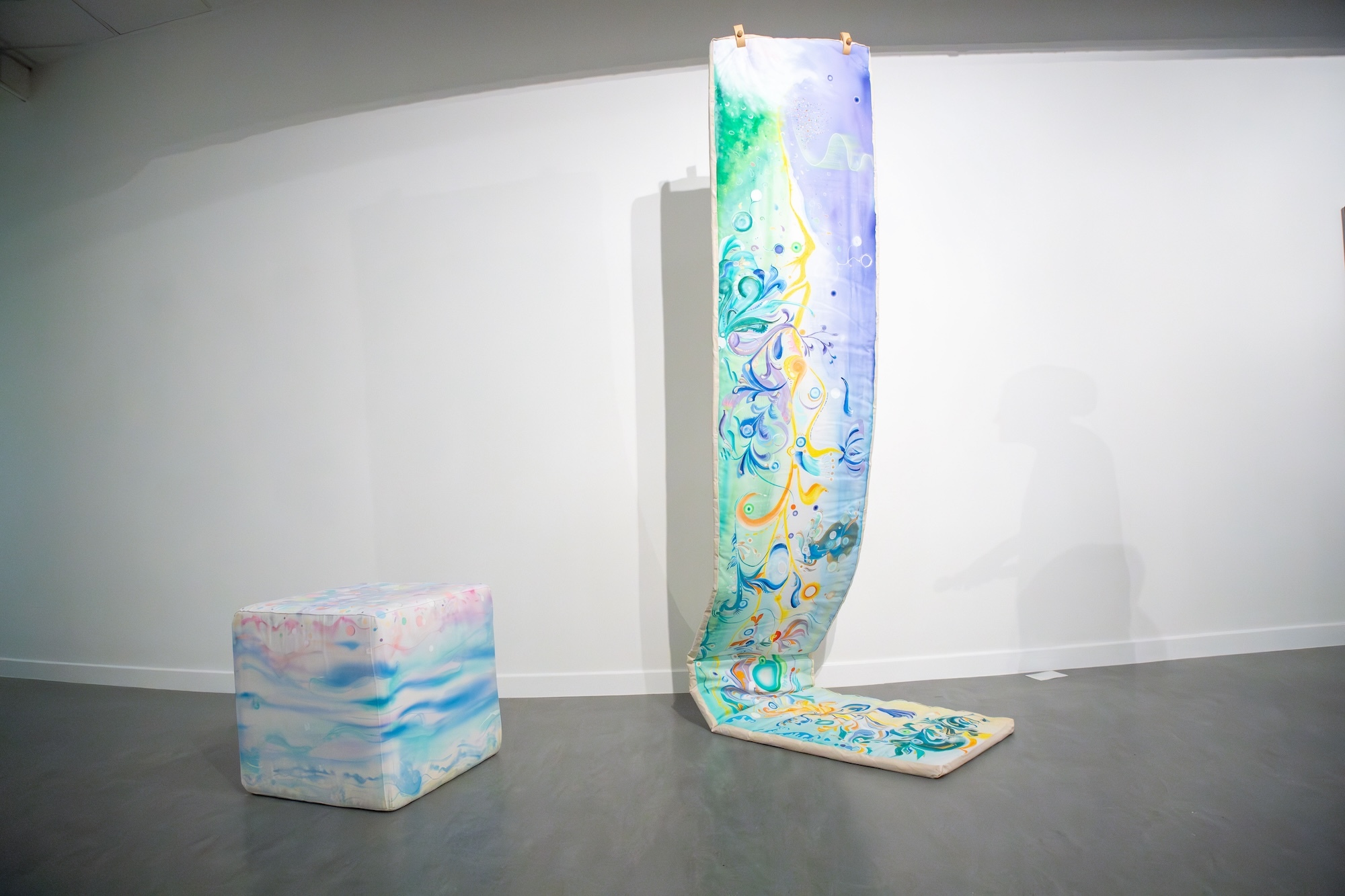 A cube and a length of fabric both with an abstract pattern painted on them, on display at Lighthouse, Poole.