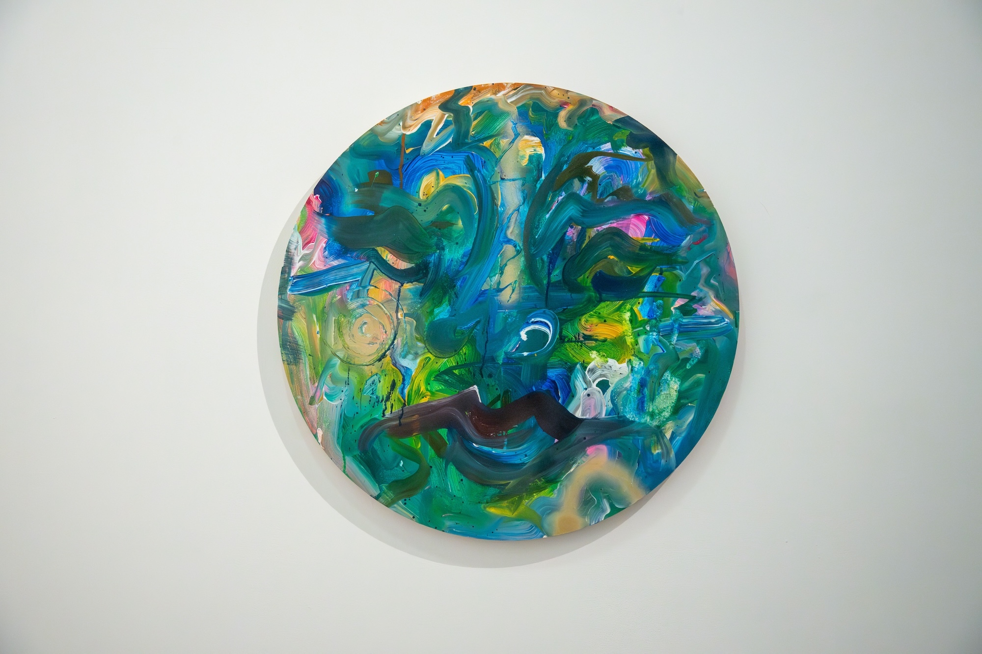 A colourful abstract painting on a small circular canvas.