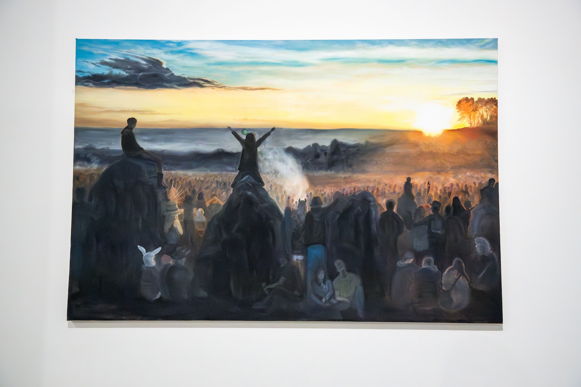 Painting of a beach festival scene with the sun rising or setting to the right.