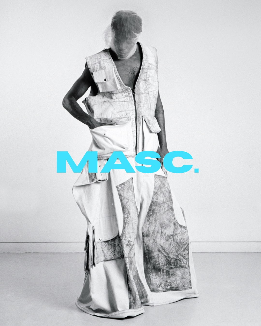 A person wearing a patchwork sleeveless outfit stands against a plain wall, overlaid with the word “MASC.” in blue.