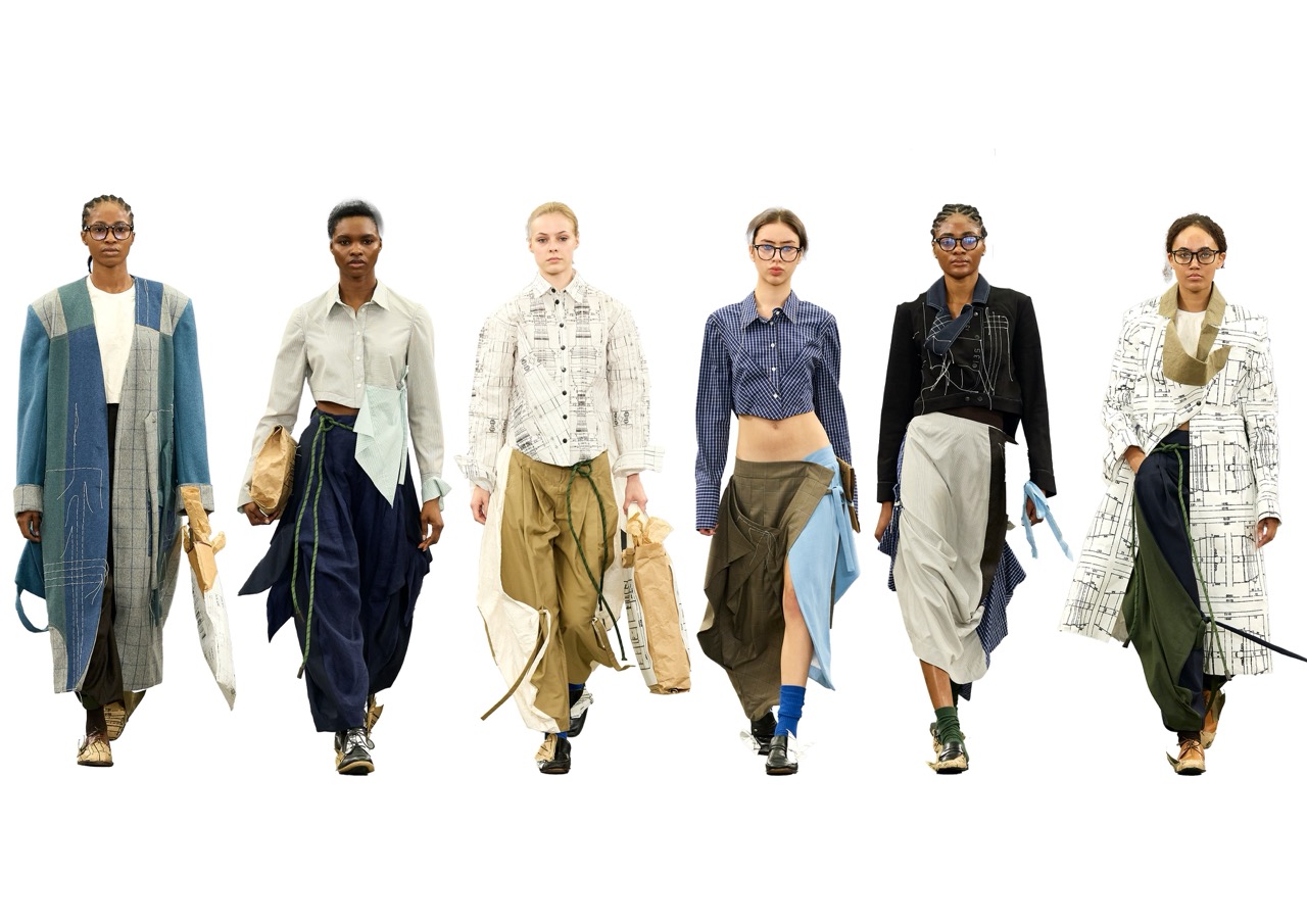 Six fashion models walk towards the camera on a white background, wearing layered neutral-toned outfits.